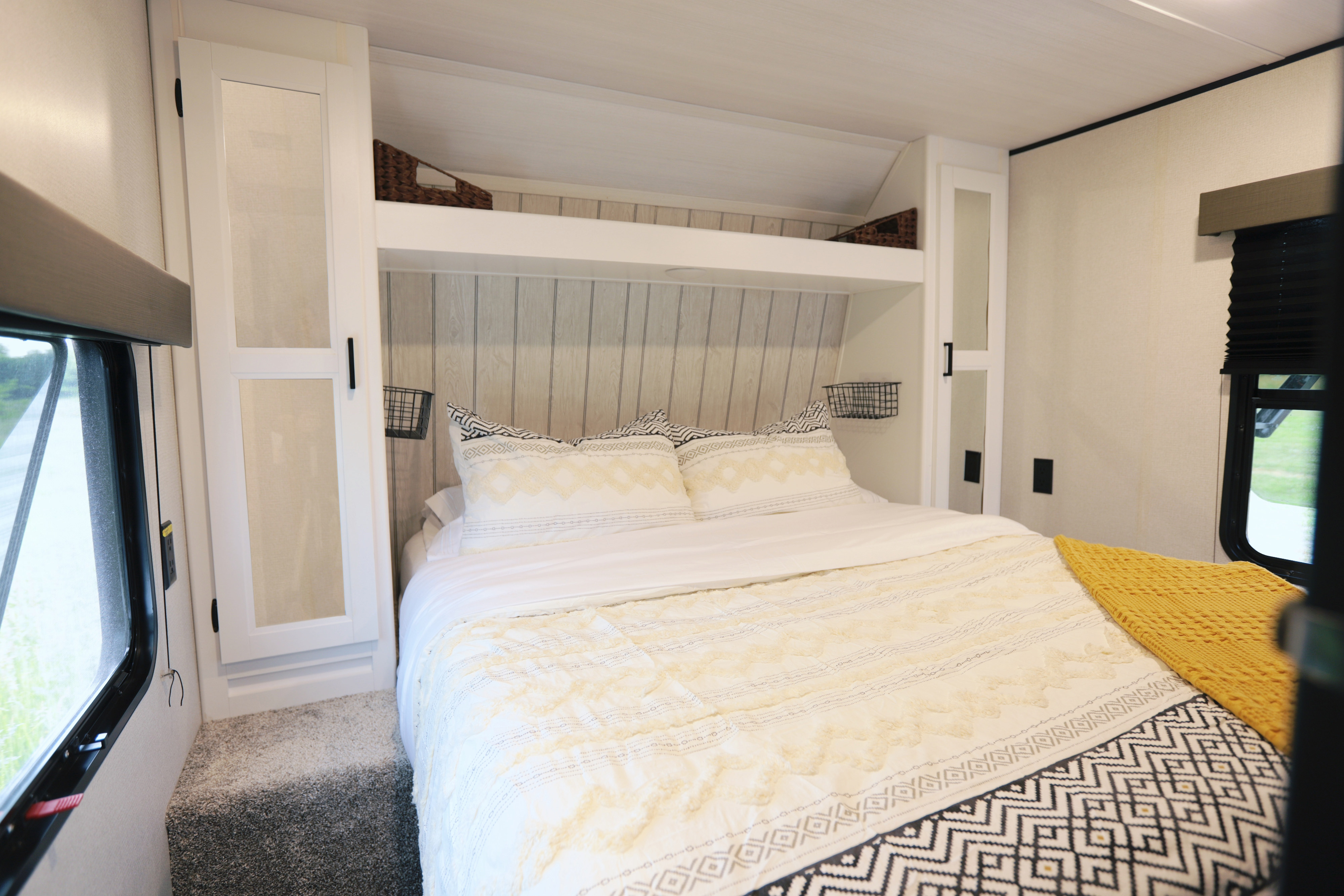 Cozy RV rental bedroom with bright patterned bedding, overhead storage, and a window, ideal for your next trip.. Keystone RV Hideout 2022