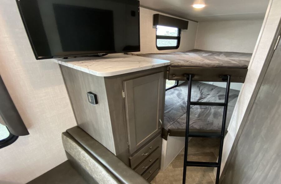 RV rental: Compact interior with TV, storage, and comfortable bunk beds with a ladder.. East to West Alta 2021