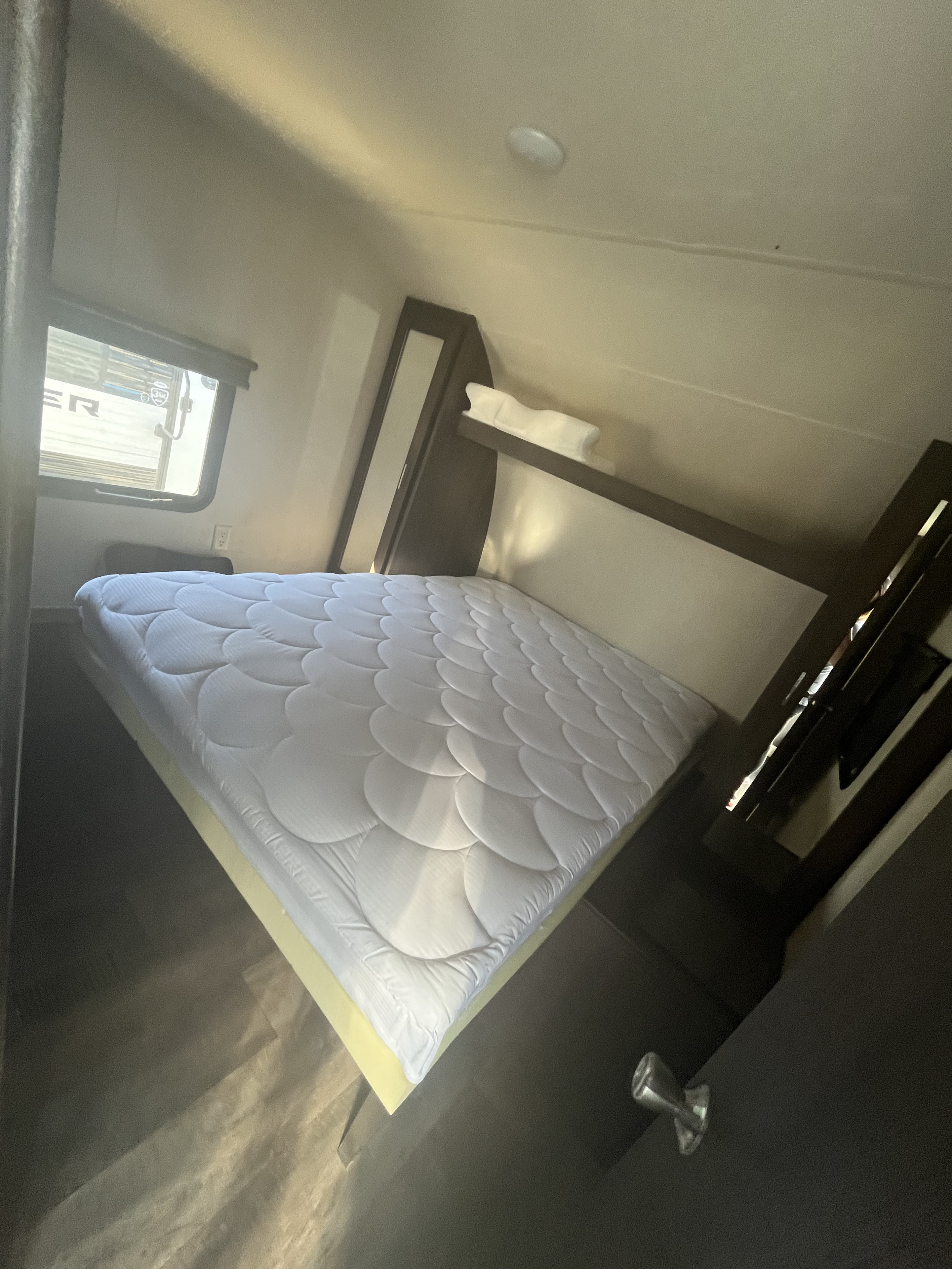 Spacious RV rental bedroom featuring a comfortable bed with a white topper, window, and built-in storage units.. Forest River Salem 2018