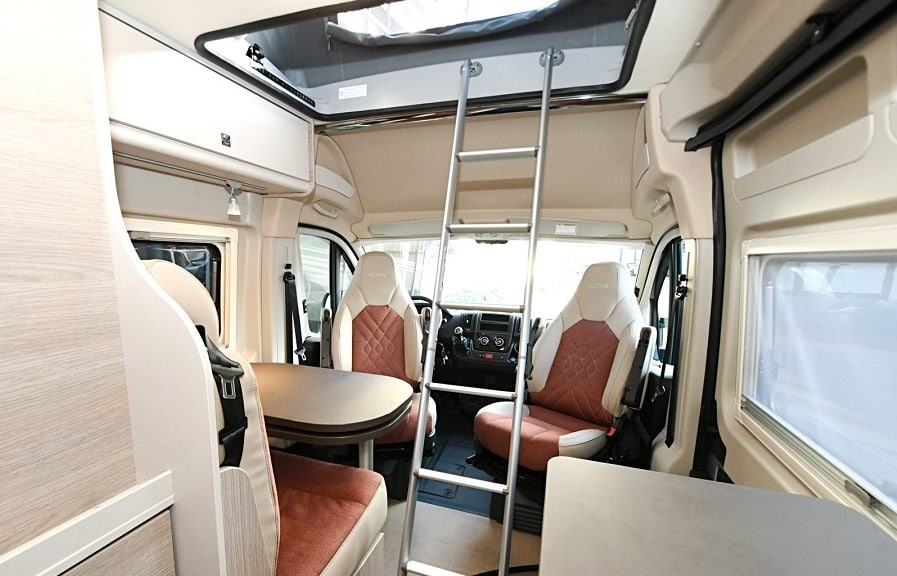 Comfortable RV rental interior with living/dining area, driver's cabin, and ladder to an overhead bed.. Bürstner CAMPEO 540 2023