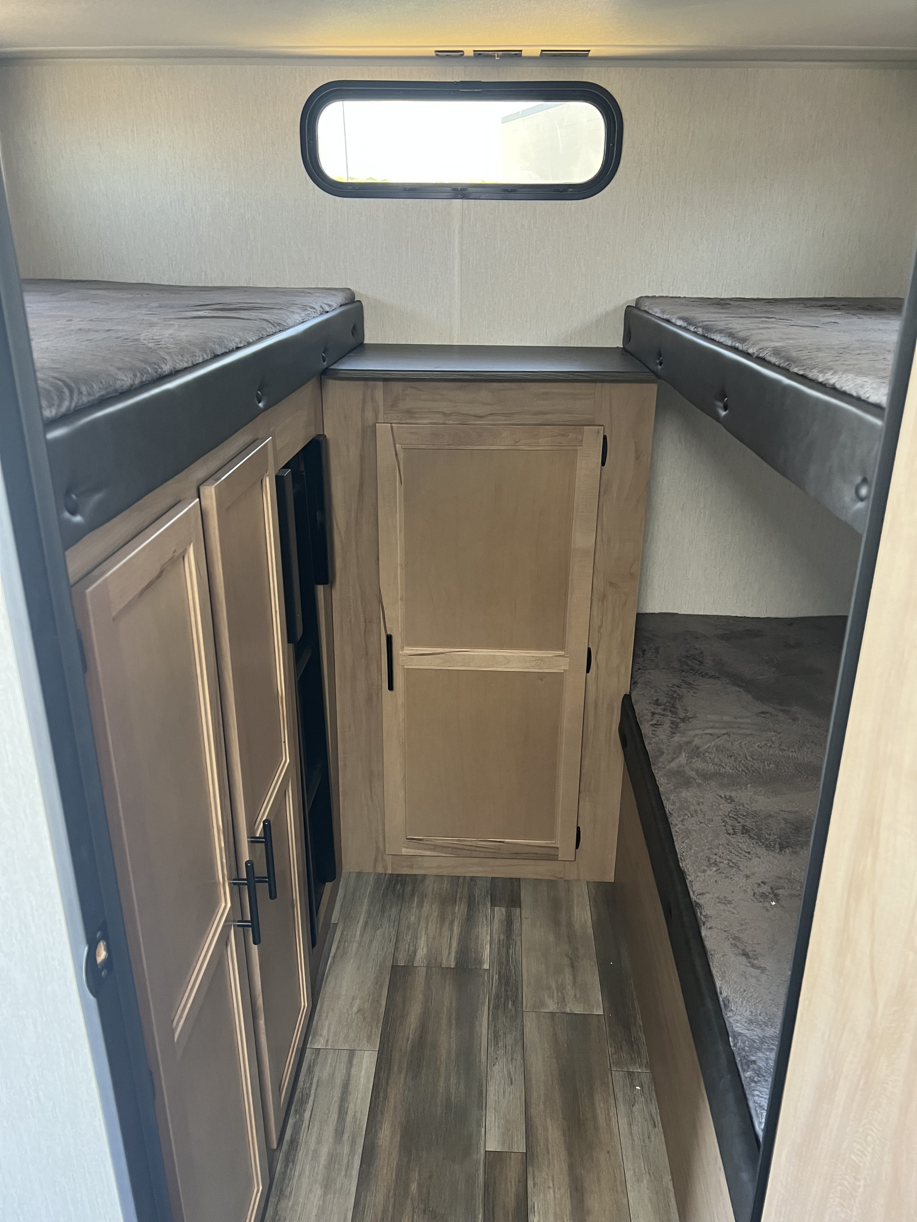 RV rental bunk beds: a cozy interior with storage cabinets, a horizontal window, and wood-look flooring for your travels.. Forest River 29TE 2023