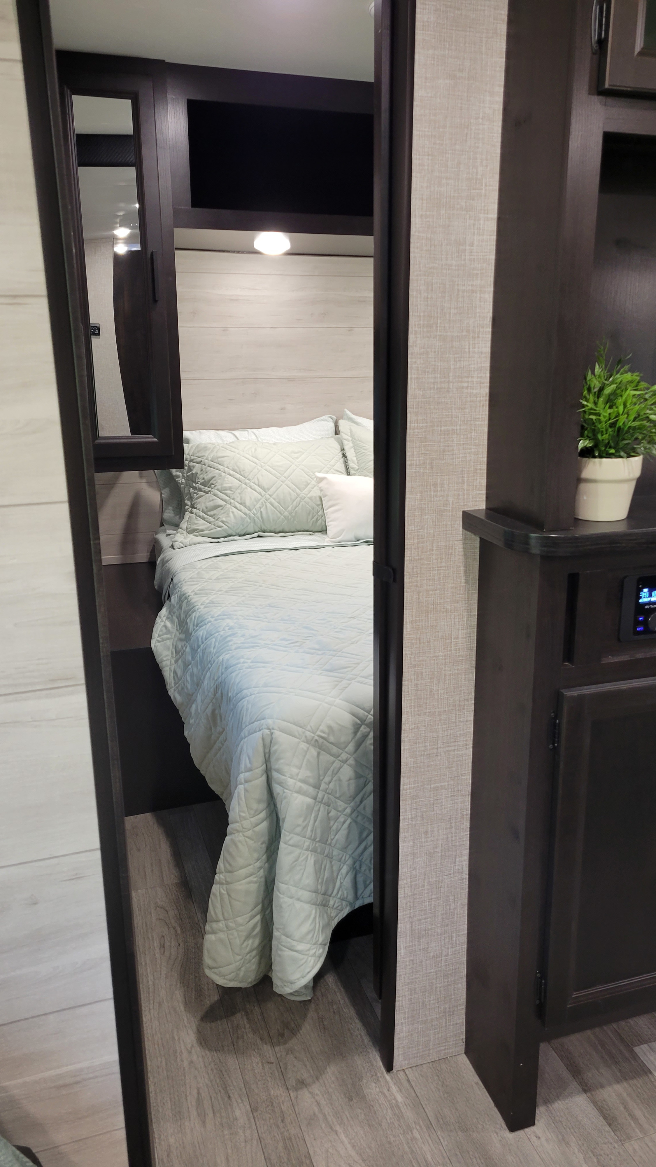 Cozy RV rental bedroom featuring light green bedding, wood-paneled walls, and practical built-in cabinetry.. Jayco Jay Flight 2023