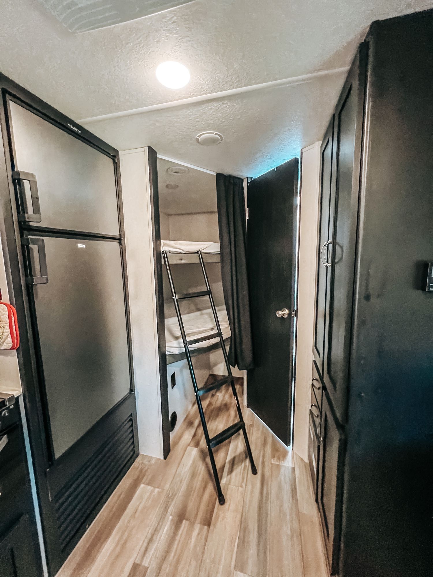 Compact RV rental interior with a Dometic fridge, bunk beds, and modern dark cabinets. Perfect for family adventures!. Coachmen 257BHS 2022