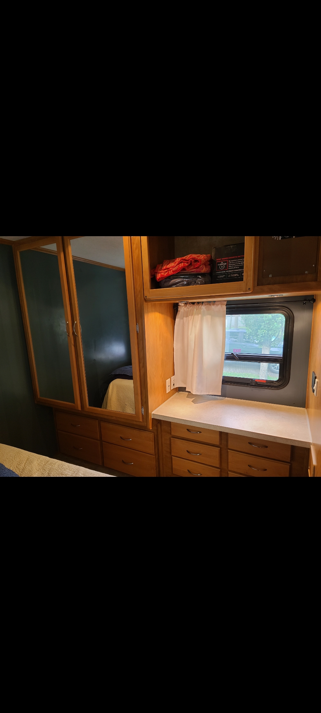 RV rental bedroom with ample wooden storage: mirrored cabinets, dresser drawers, countertop, and a window for natural light.. Fleetwood Other 2006