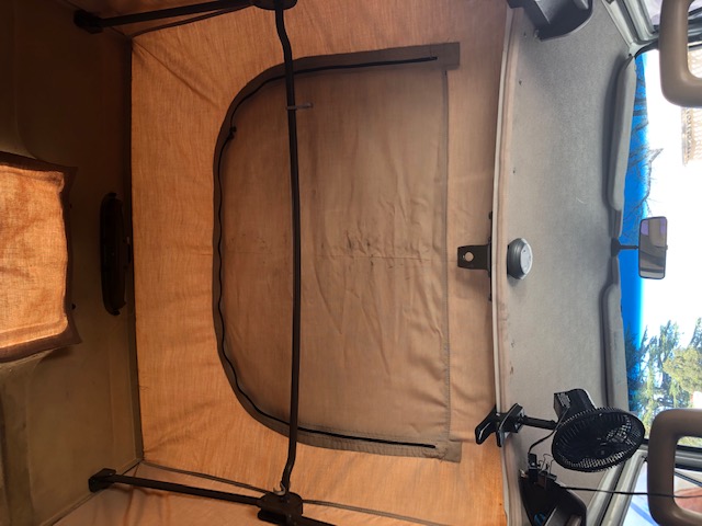 View inside an RV rental: Pop-top camper bed area stretches to the front cabin and windshield, featuring a fan.. Volkswagen Westfalia 1985