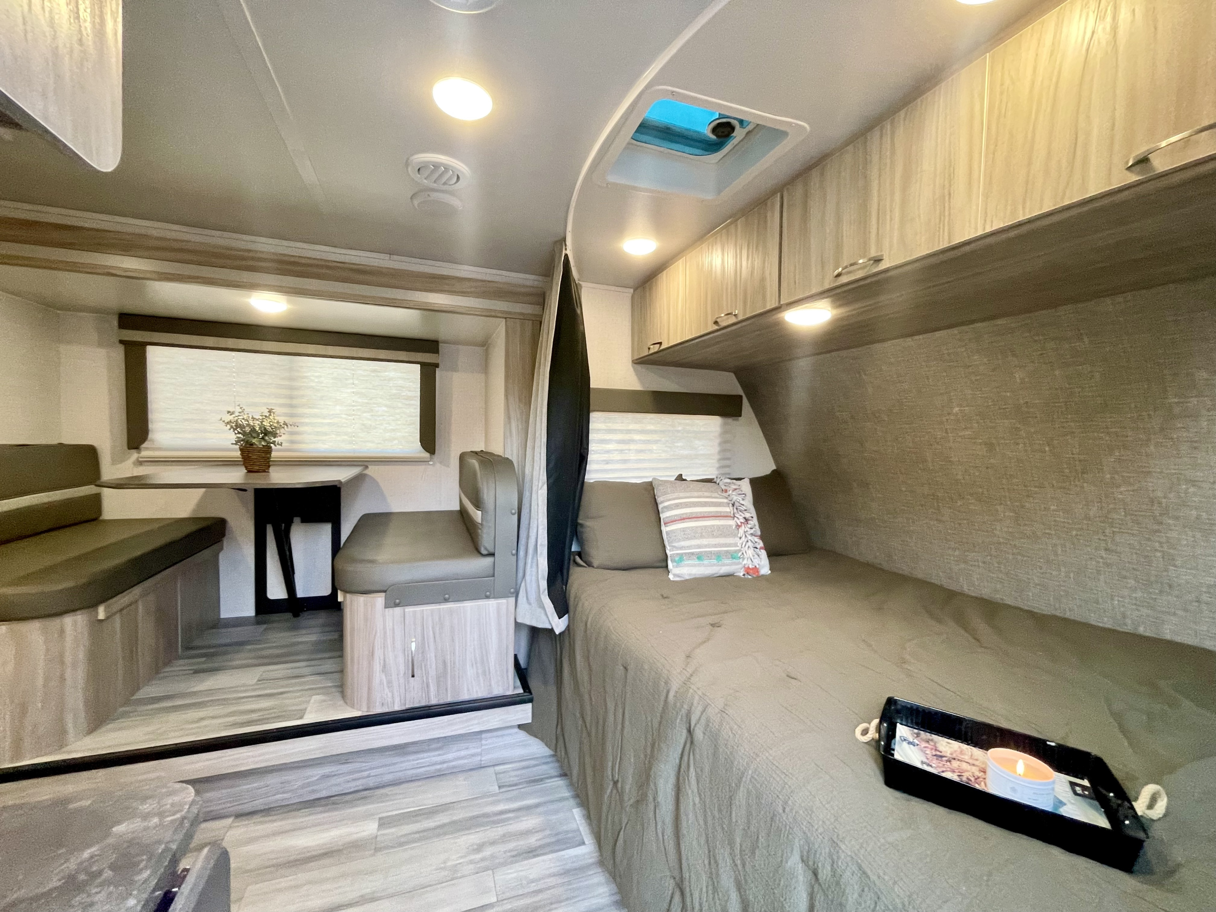 RV rental: Interior showing a bed with a tray, dinette, and overhead storage, designed for comfortable travel.. Winnebago Micro Minnie 2022