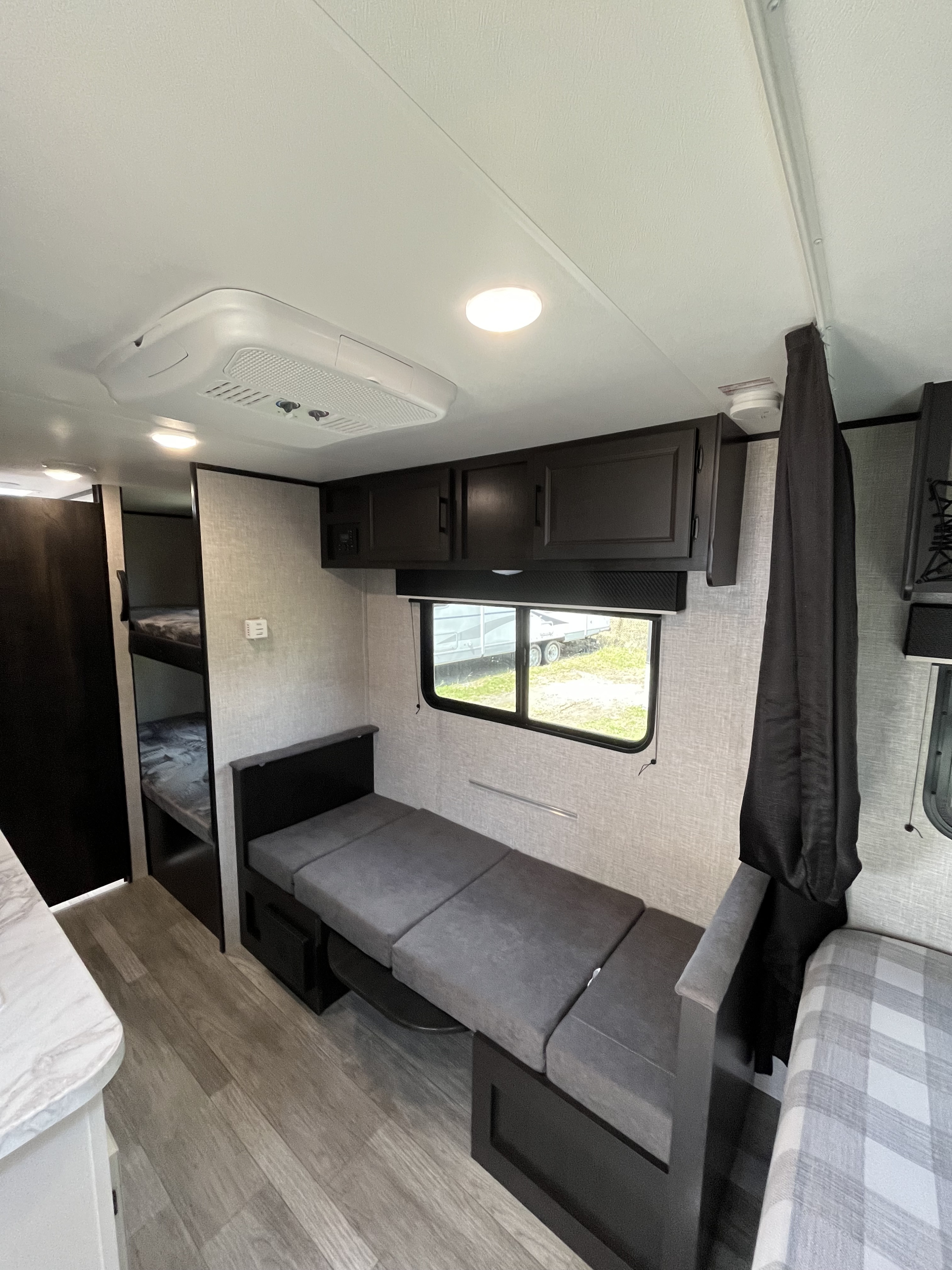 RV rental interior featuring bunk beds, a sofa/dinette area, overhead storage, and an AC unit. Light wood floor.. Jayco Jay Flight SLX 2022