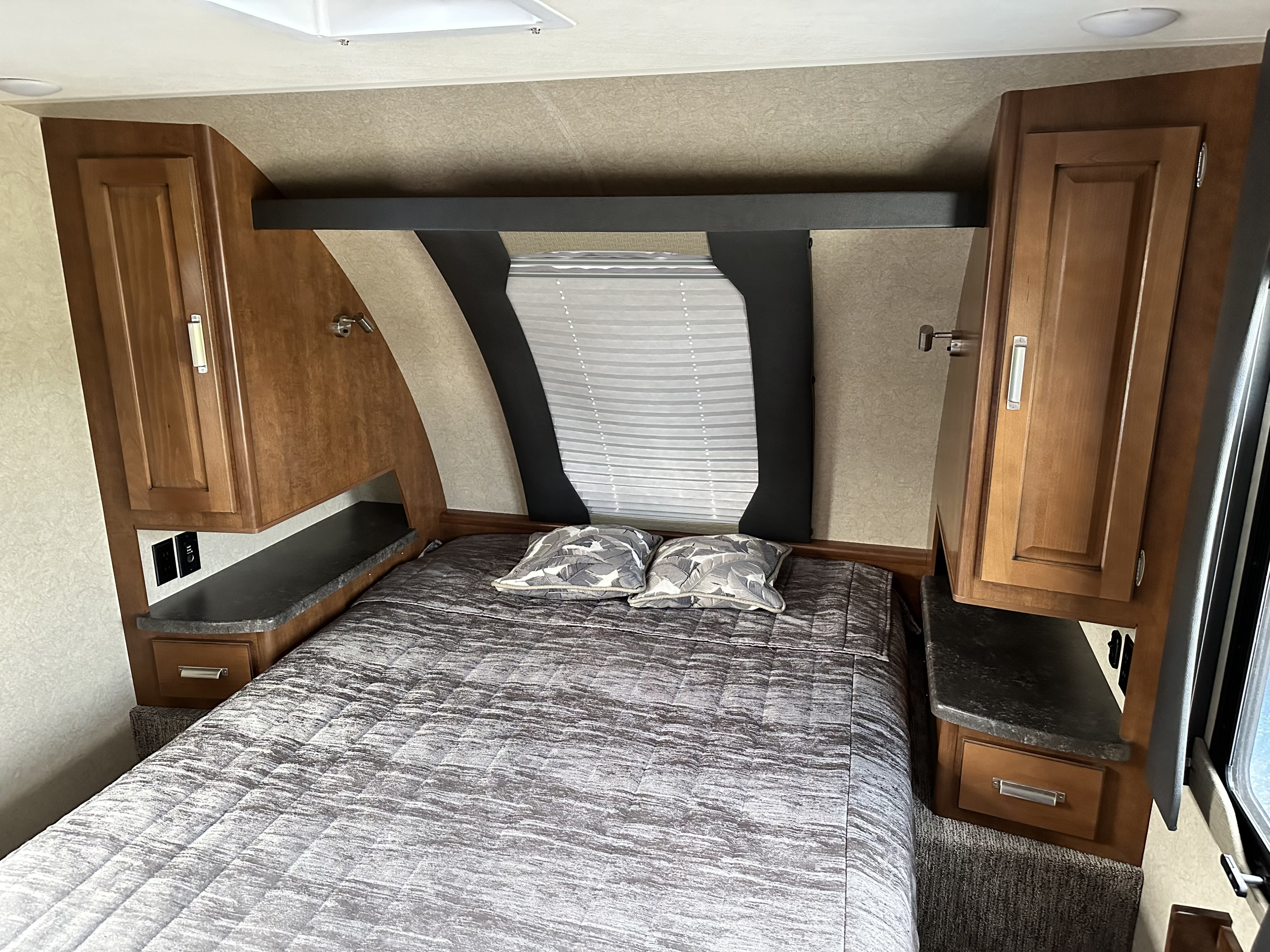 This inviting RV rental bedroom features a comfy bed, overhead cabinets, reading lights, and bedside power outlets.. Lance Manufacturing Lance Manufacturing Trailer 2018