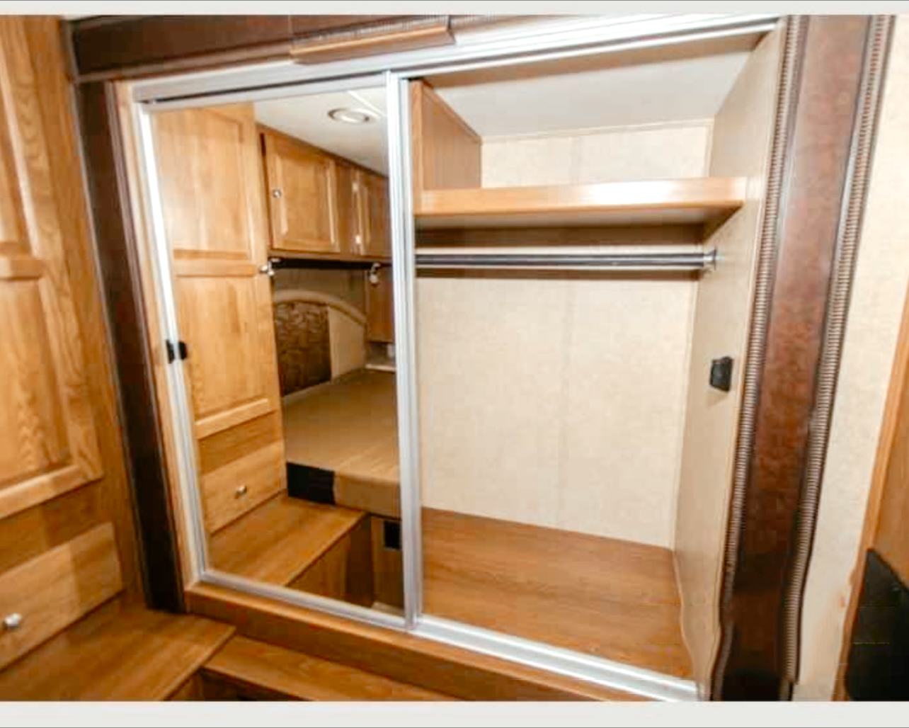 RV rental interior: Wooden cabinetry, a spacious closet with sliding doors, and a raised sleeping area beyond.. Forest River Coachmen Leprechaun 2017