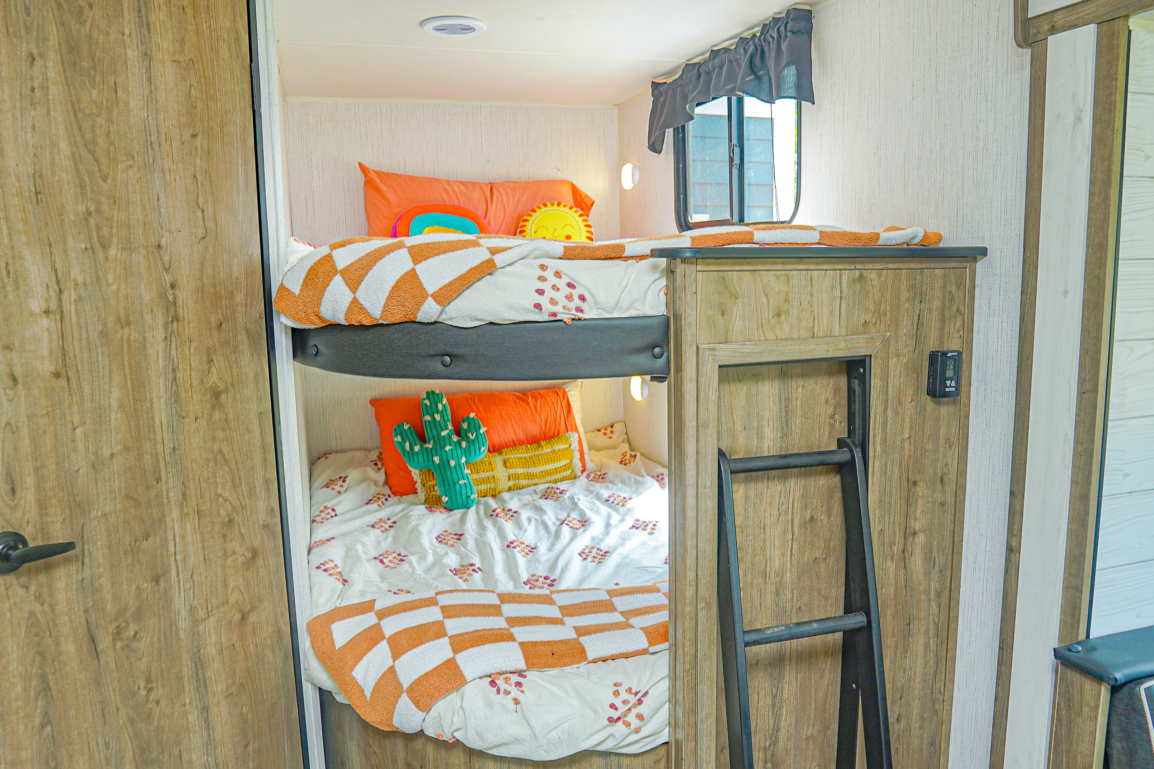Cozy RV rental bunk beds with colorful decor, including sun and cactus pillows. Ideal compact sleeping area for trips.. Heartland RVs Pioneer 2023
