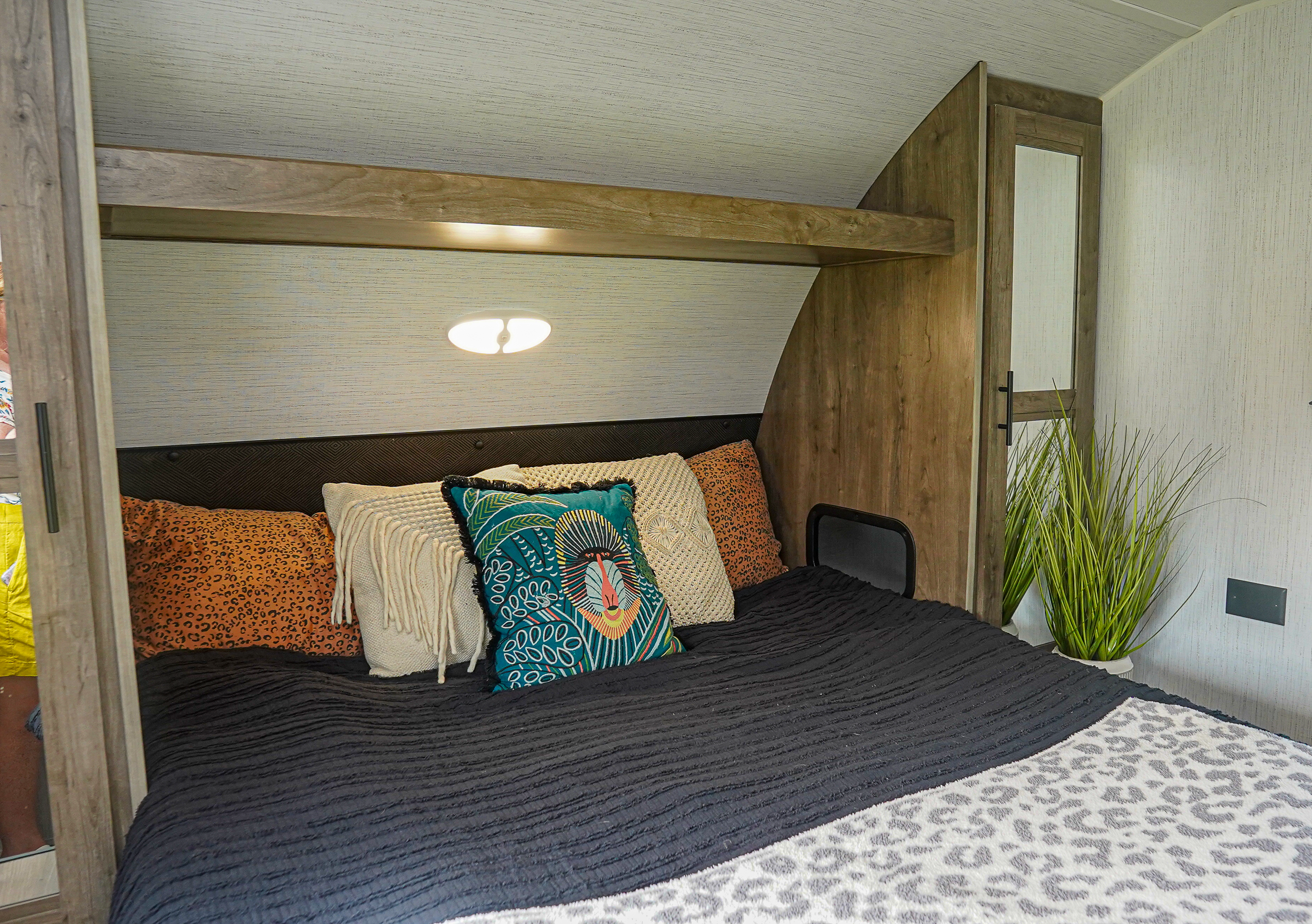 Cozy RV rental bedroom showcasing a dark textured bedspread, vibrant pillows, and rich wood finishes.. Heartland RVs Pioneer 2023
