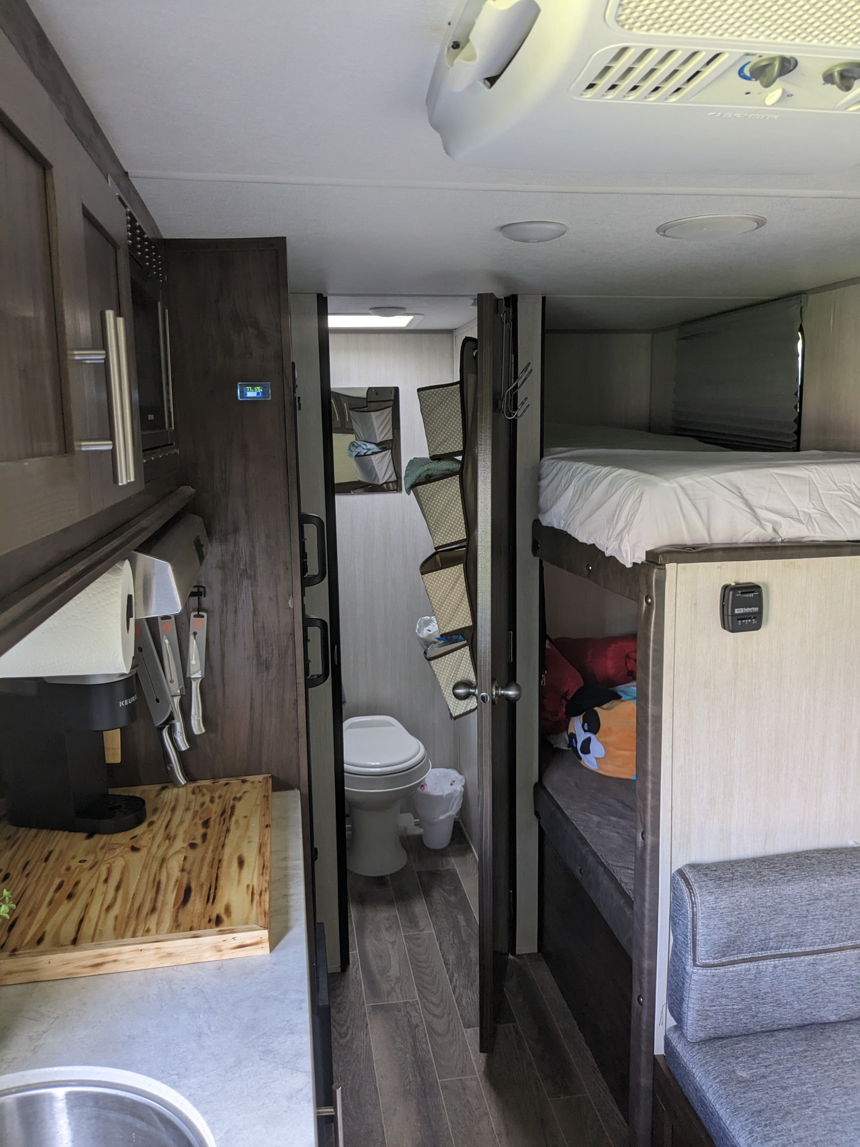 RV rental interior: A compact kitchen, an open bathroom door leading to a toilet, and bunk beds.. Forest River Cherokee Wolf Pup 2019