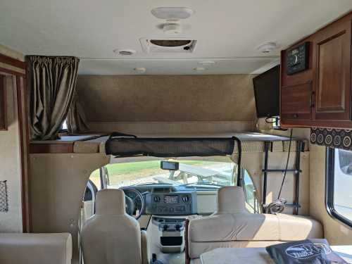 Spacious RV rental interior featuring an overhead bunk, cockpit area, and TV for comfortable travel.. Forest River Sunseeker 2016