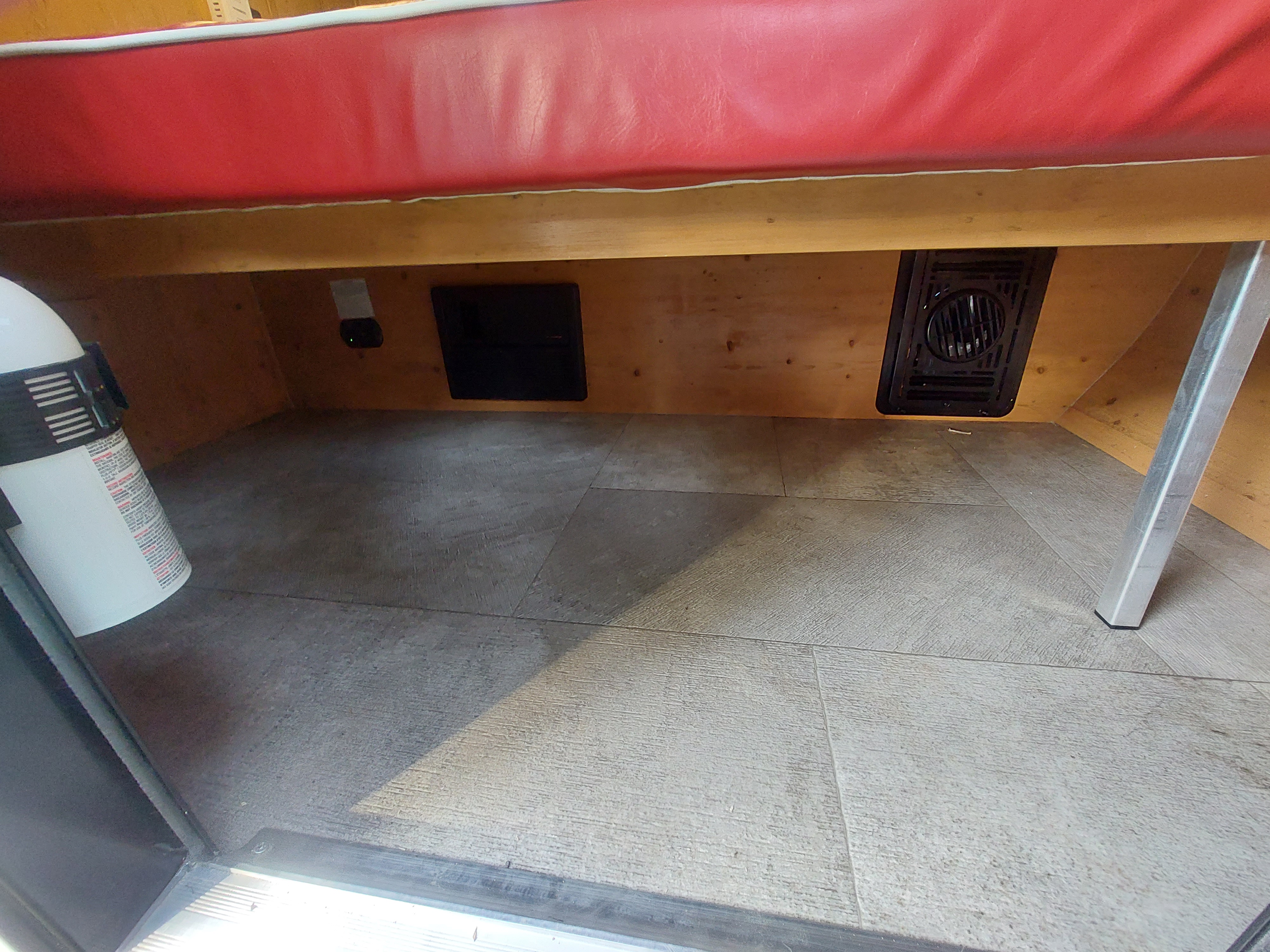 RV rental under-seat storage area, featuring a fire extinguisher, ventilation, and an access panel.. Sunset Park RV SunRay 2022