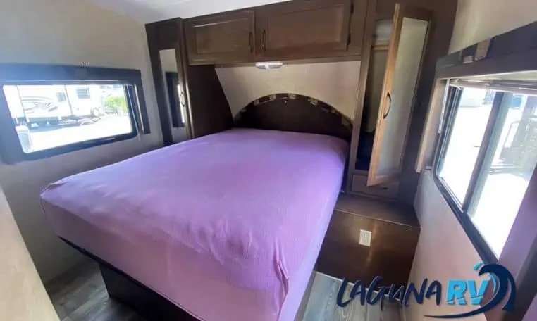 Spacious RV bedroom for your next RV rental adventure. Features include a purple bed, ample storage, and large windows.. Pacific Coachworks Blaze'N 2015