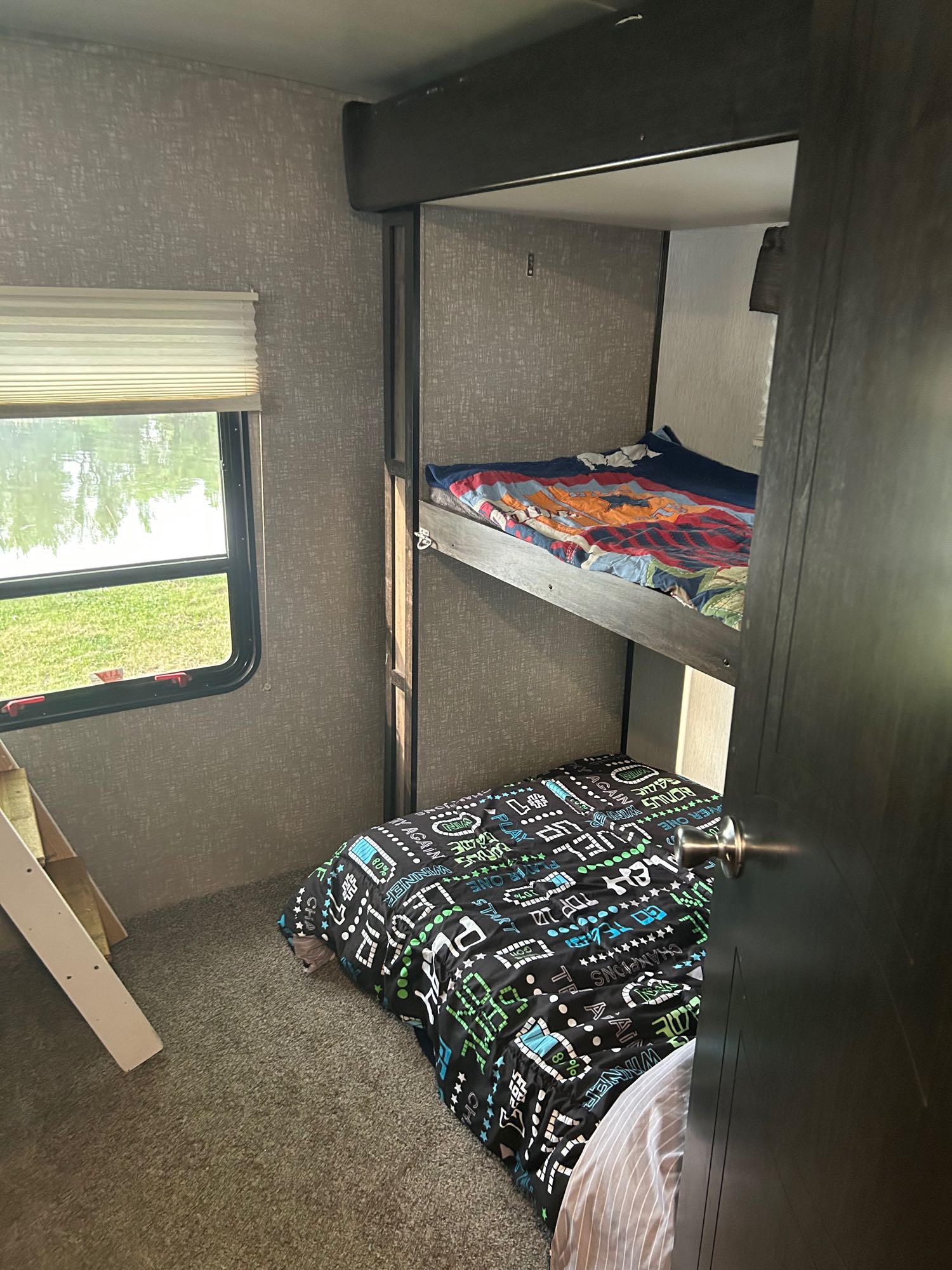 Step inside this RV rental's bunk room. Features two stacked beds, a window with lake and grass views.. Heartland RVs Mallard 2020