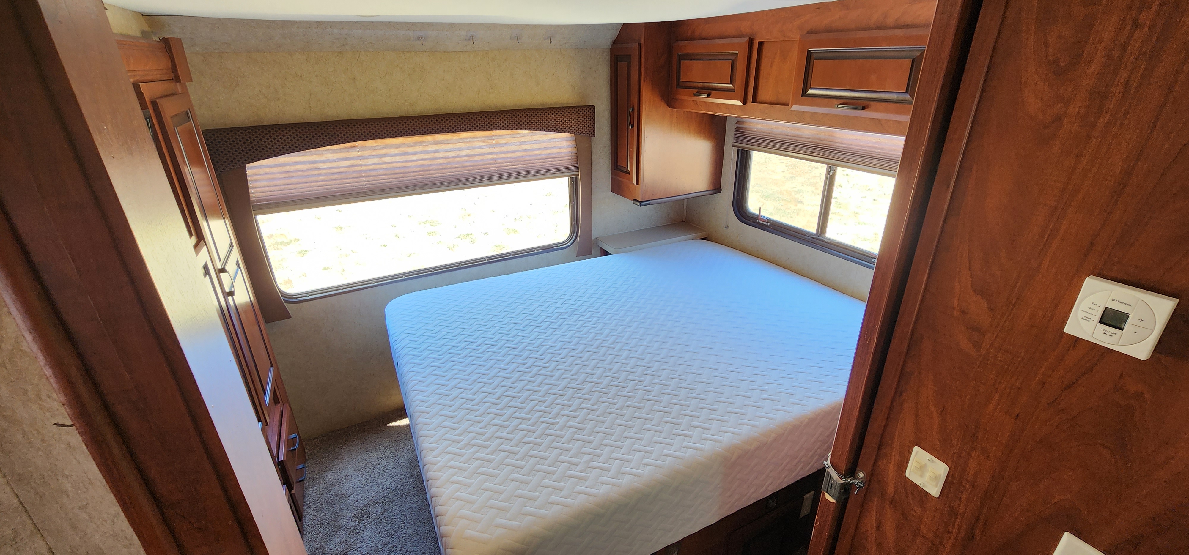 Bright RV rental bedroom: Features a comfortable bed, large windows, wooden cabinetry, and a Dometic climate control system.. Forest River Forester 2013