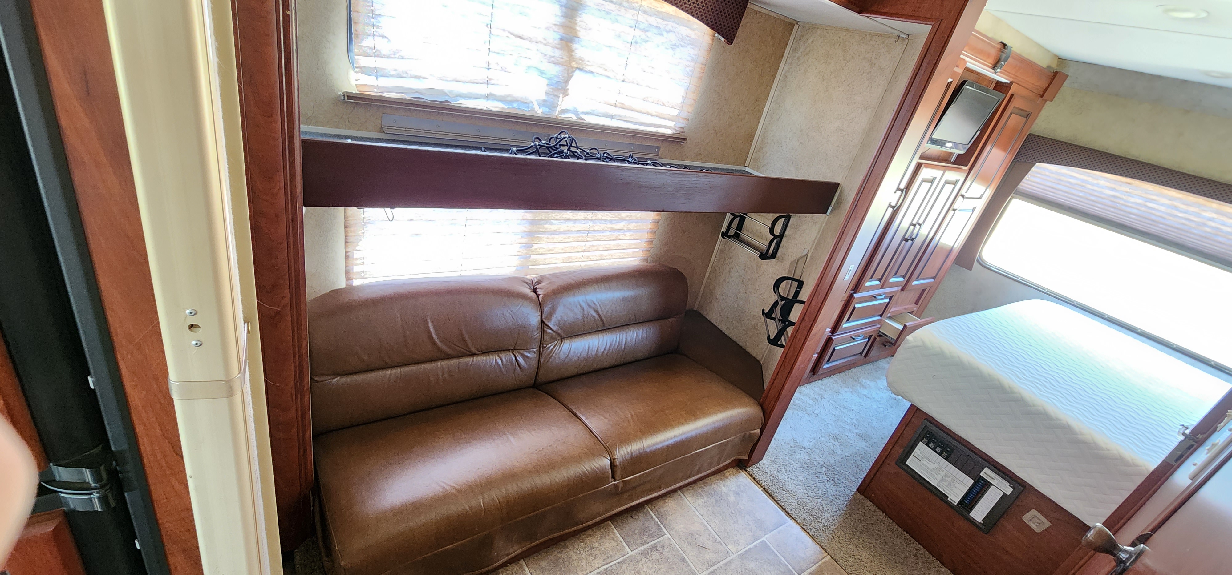 RV rental interior: brown sofa, overhead bunk, and a cozy bedroom with a white mattress & wooden storage.. Forest River Forester 2013