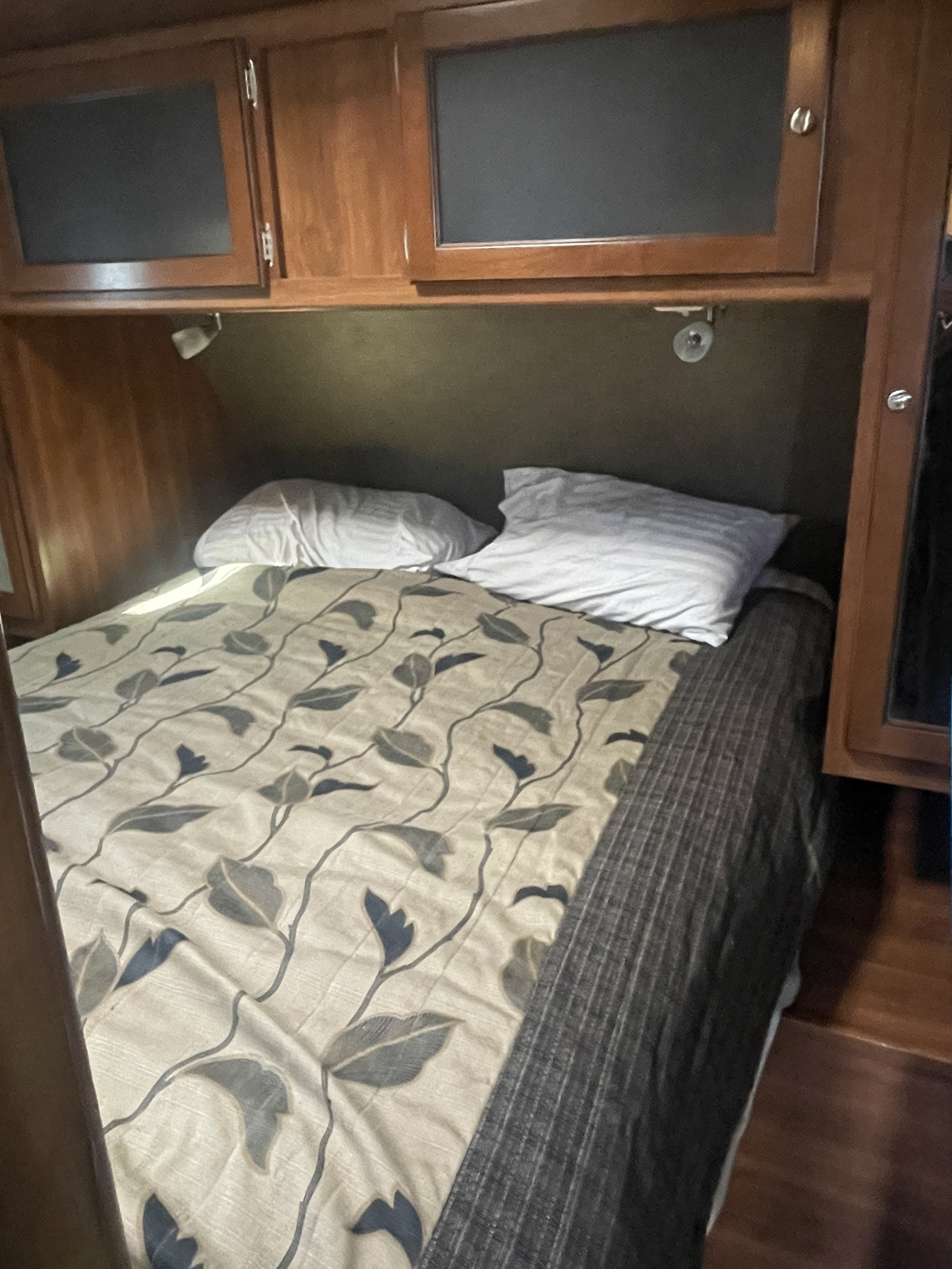 Comfortable RV rental bedroom with patterned comforter, pillows, and overhead storage cabinets.. Keystone RV Bullet Premier Ultra 2014