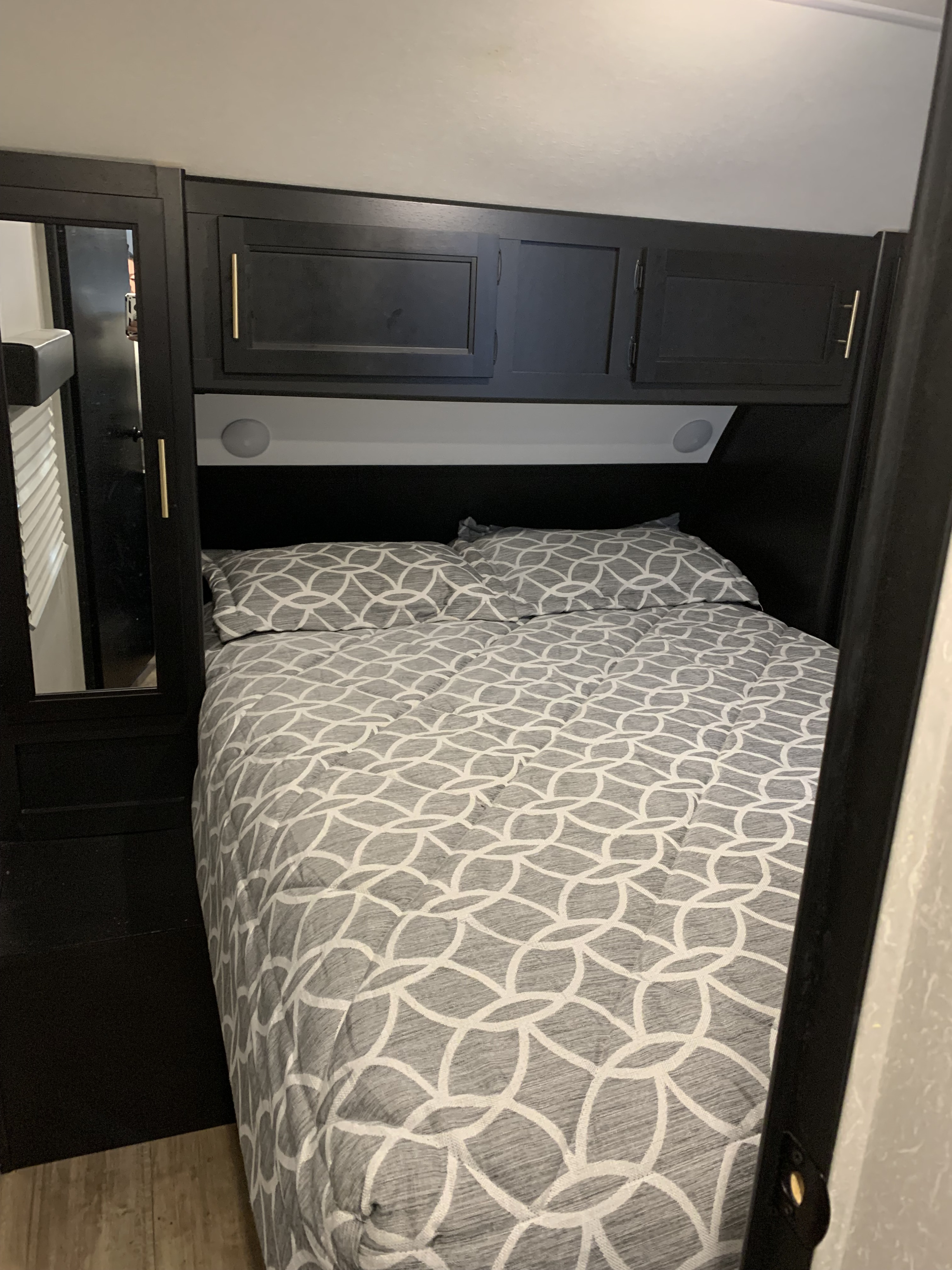 This inviting RV rental bedroom features a comfy bed with modern gray bedding, dark cabinets, and a mirrored wardrobe.. Forest River Cherokee Grey Wolf Black Label 2021