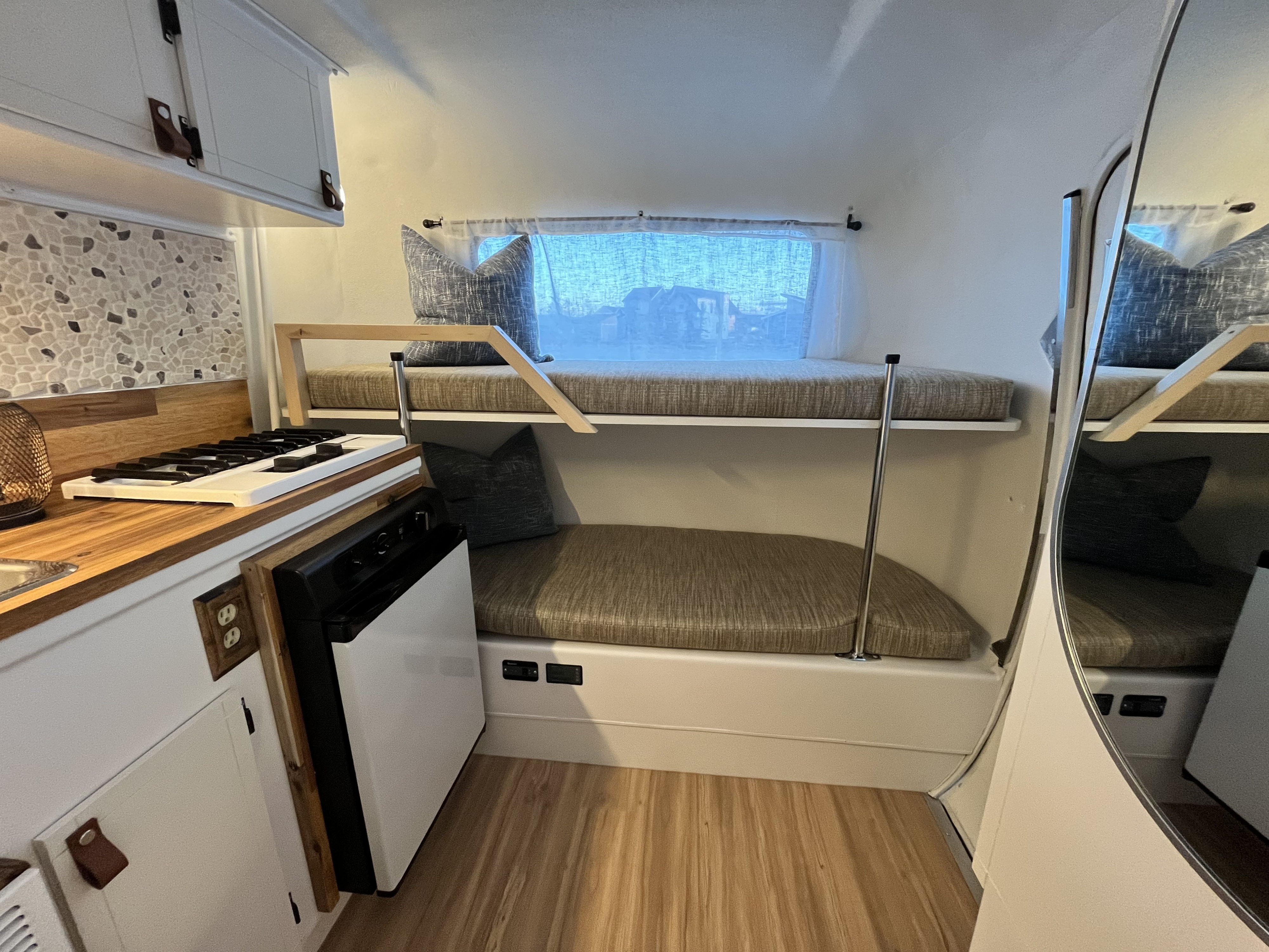 Cozy RV rental interior featuring bunk beds, a compact kitchen, and wood accents, perfect for adventure.. Other Other 1973