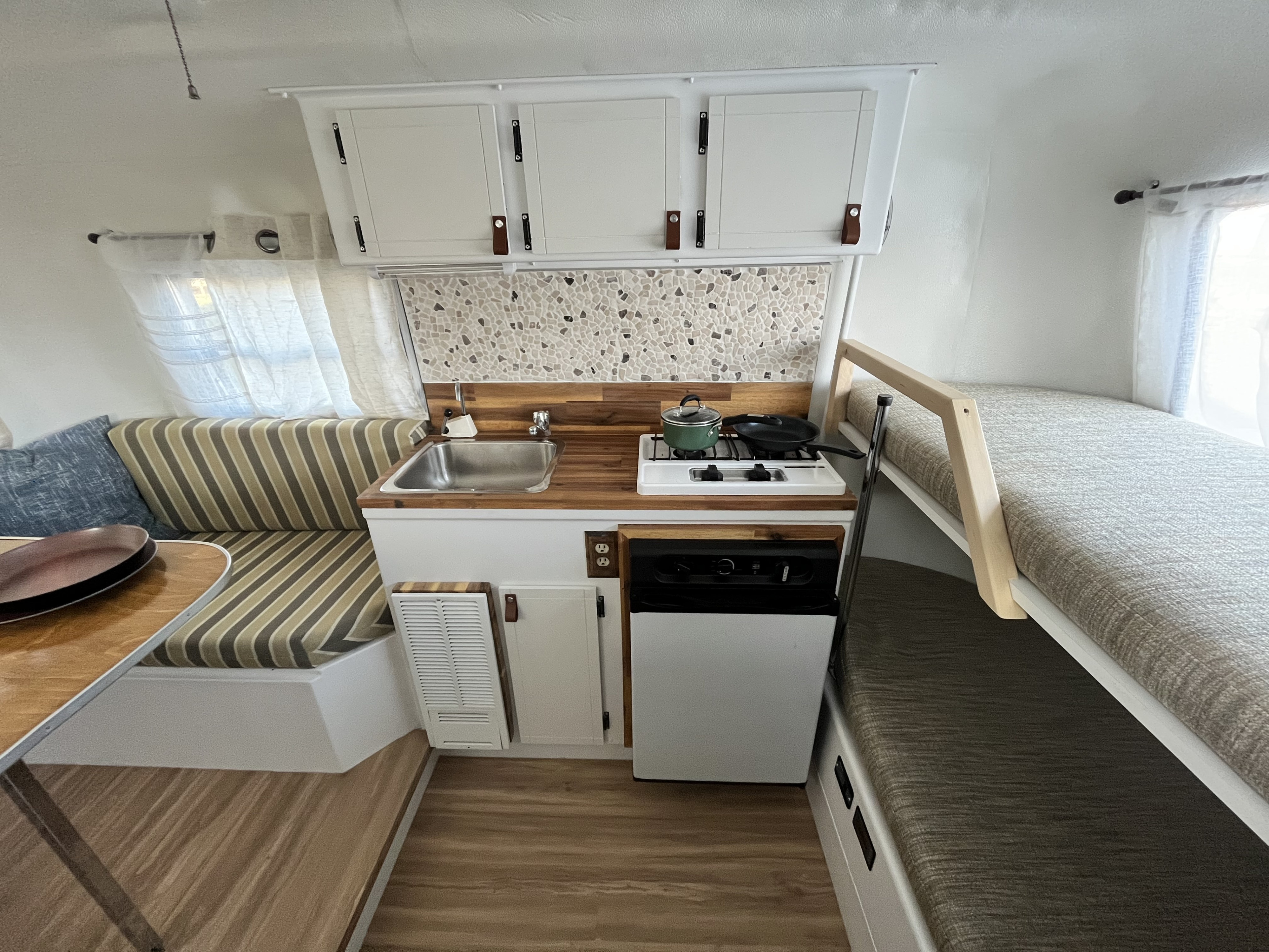 Inside a modern RV rental: a compact kitchen, dining area, and bunk beds offer a comfortable, efficient space.. Other Other 1973