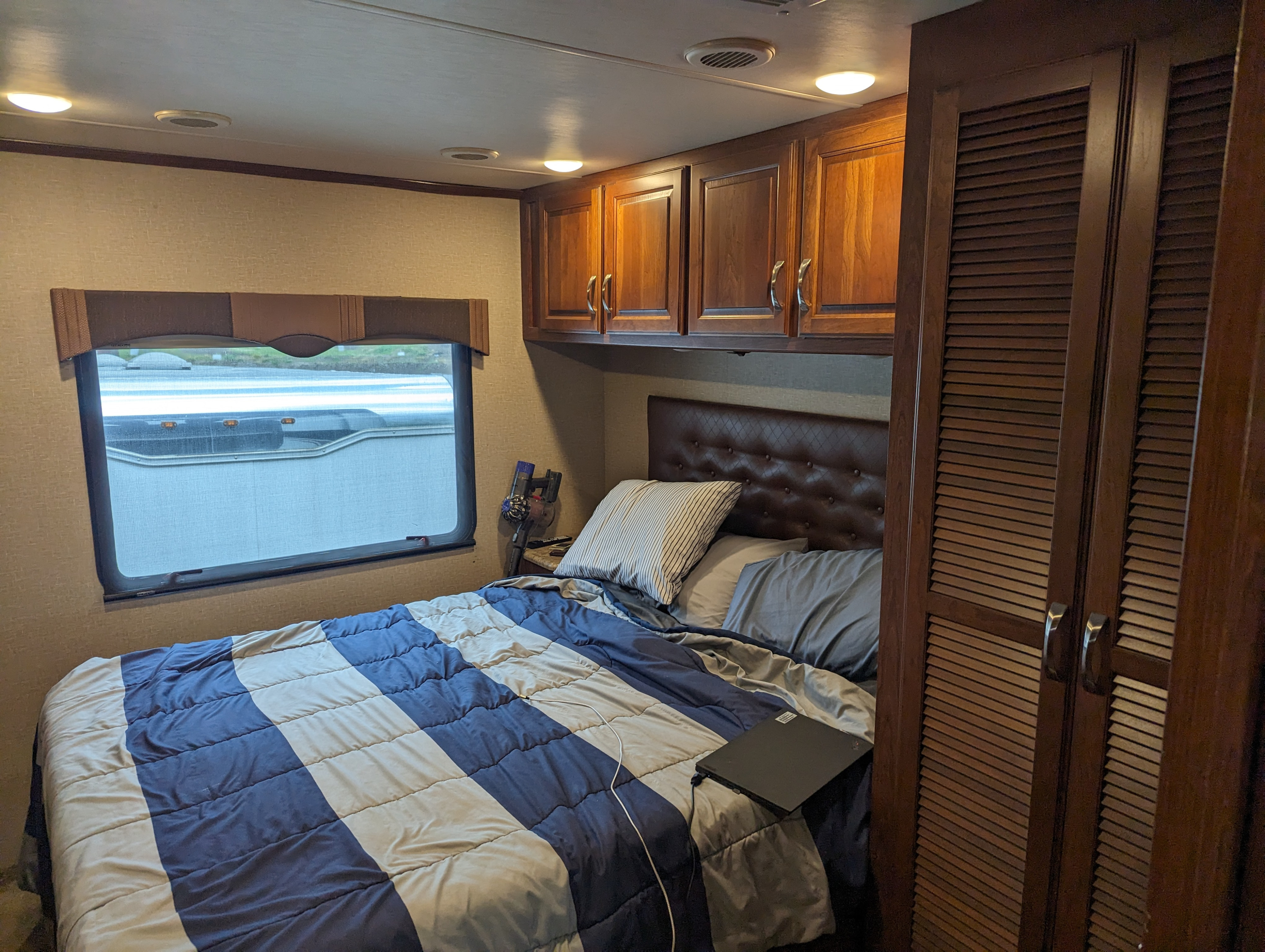 Dark wood accents and cozy bedding in this comfortable RV rental bedroom, perfect for your next mobile adventure.. Dynamax Force 2015