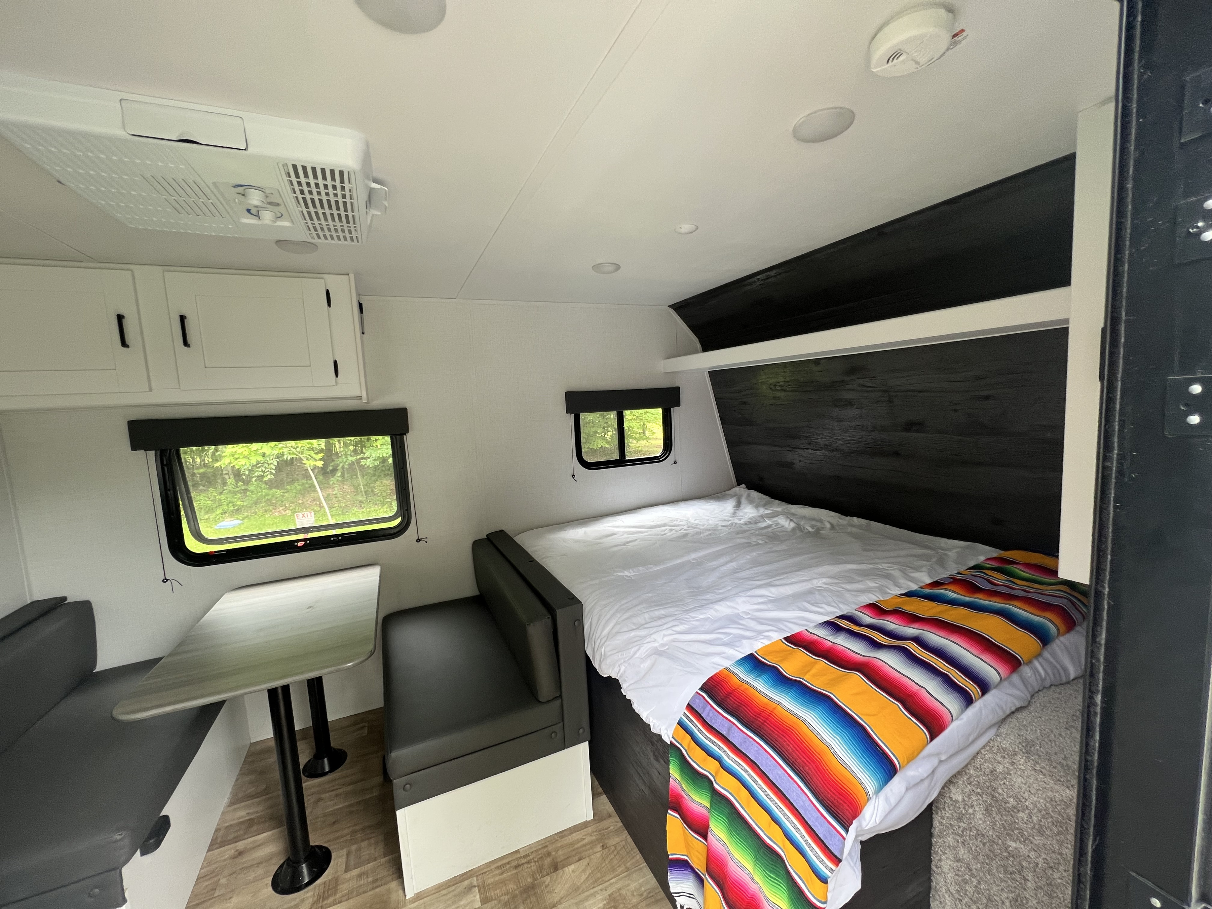 Clean RV rental interior featuring a comfortable bed, dinette area, and windows with scenic views.. Keystone RV Hideout 2023