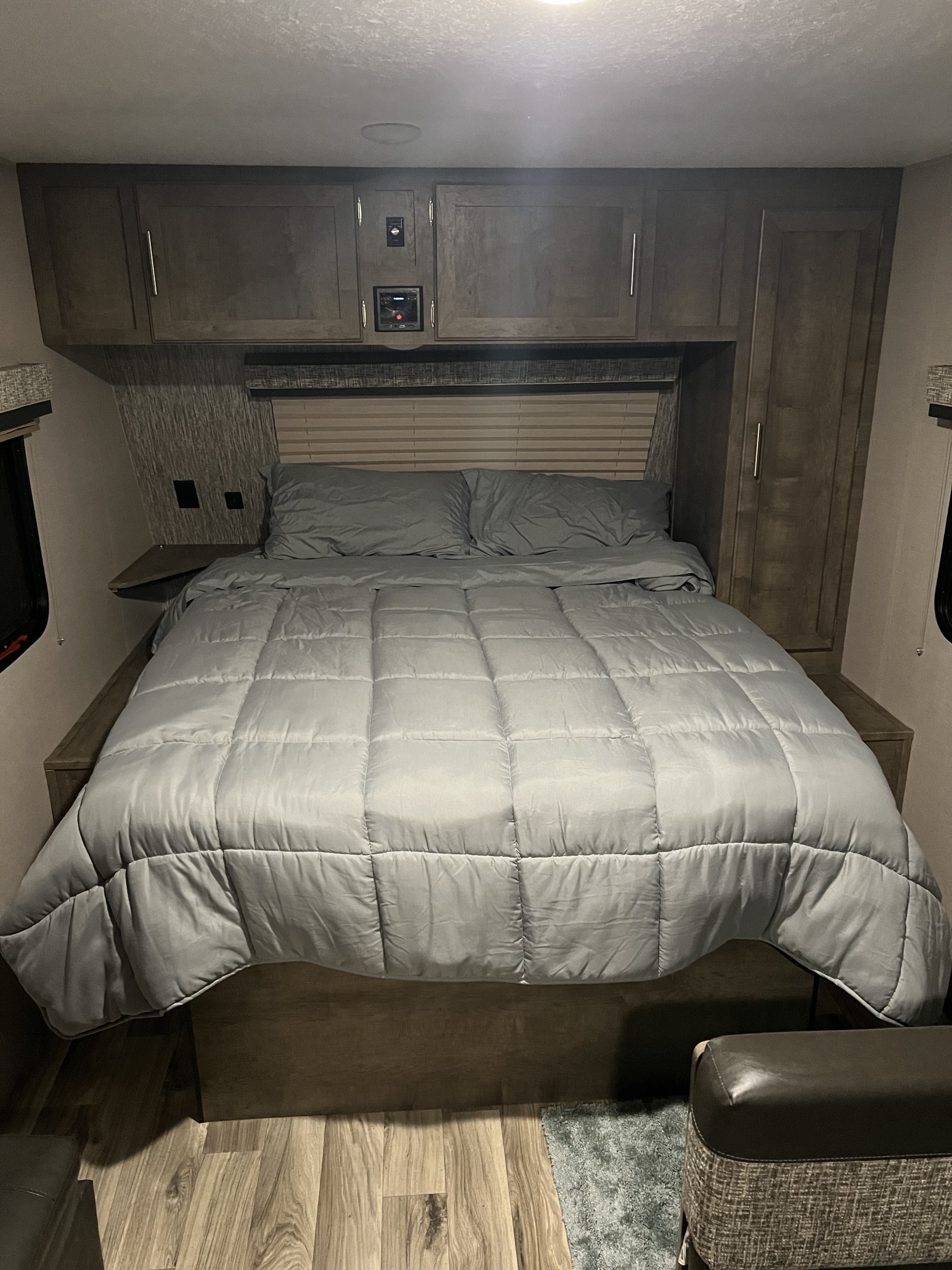 RV rental bedroom with a comfy bed, light grey bedding, ample overhead storage, and wood-look floor.. K-Z Manufacturing Escape 2020