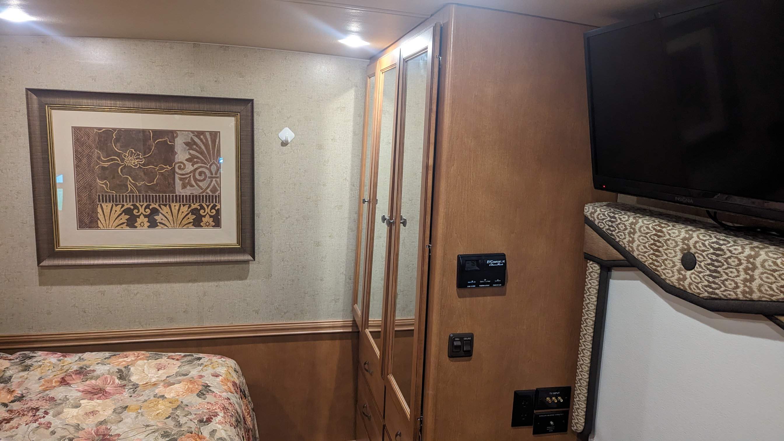 Step inside this RV rental's bedroom: floral bedding, mirrored wardrobe, TV, and essential climate controls visible.. Itasca Sunova 2014