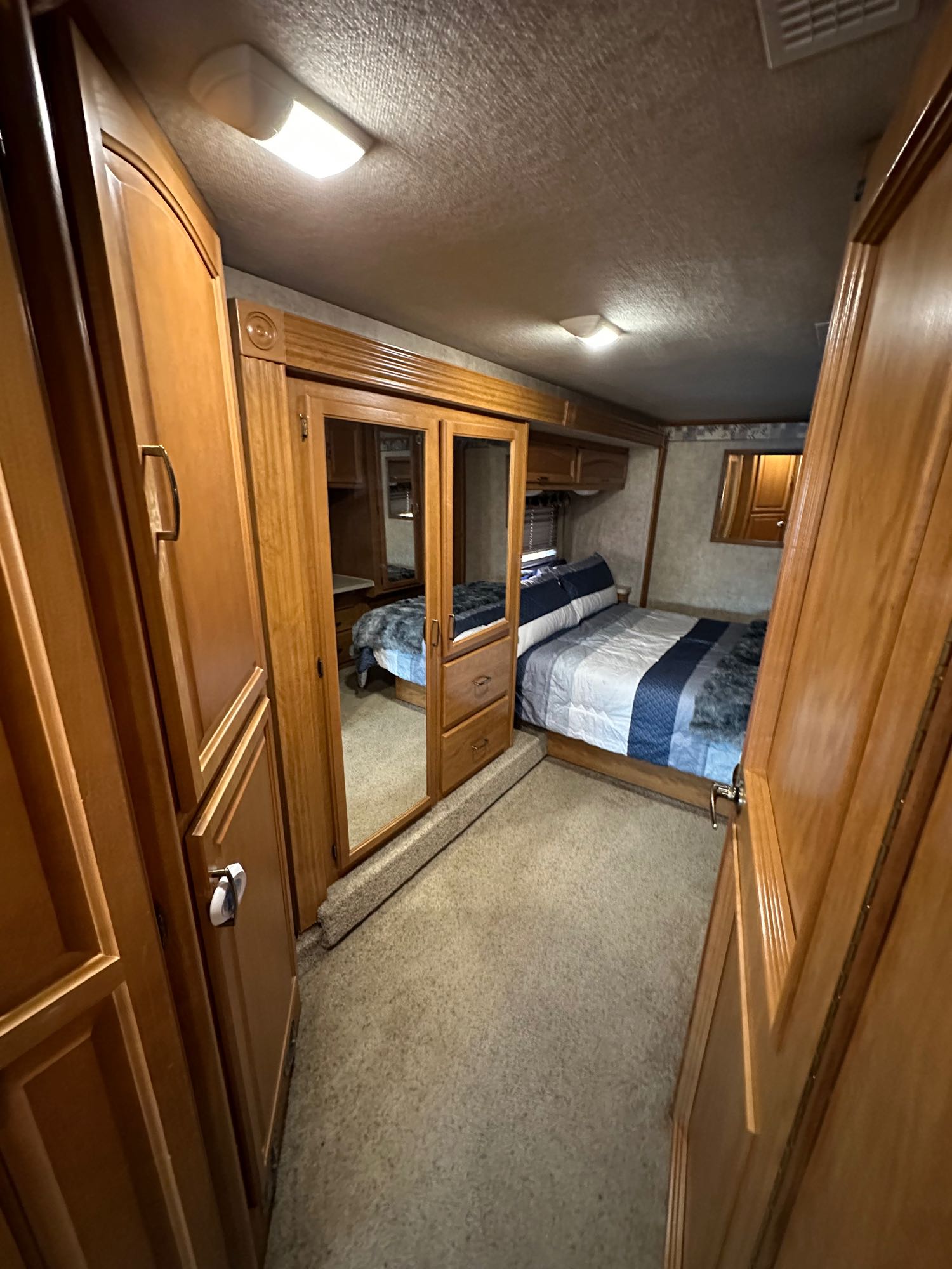 Cozy RV rental bedroom with a bed, wooden cabinets, and mirrored wardrobe for a comfortable stay.. Fleetwood Terra 2007