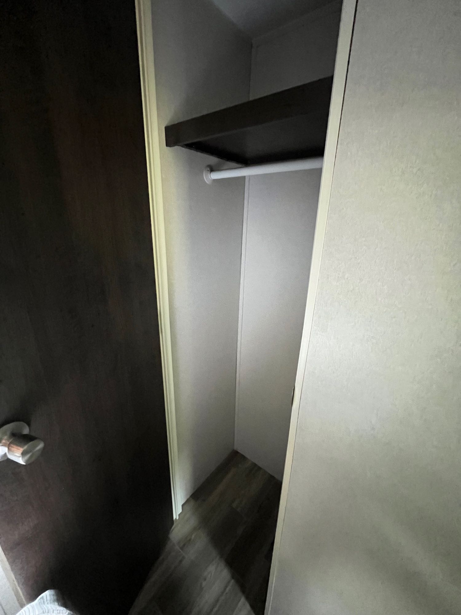 Empty RV rental closet with shelf & hanging rod, featuring a wood-look floor, offering practical storage space.. Forest River Wildwood 2019