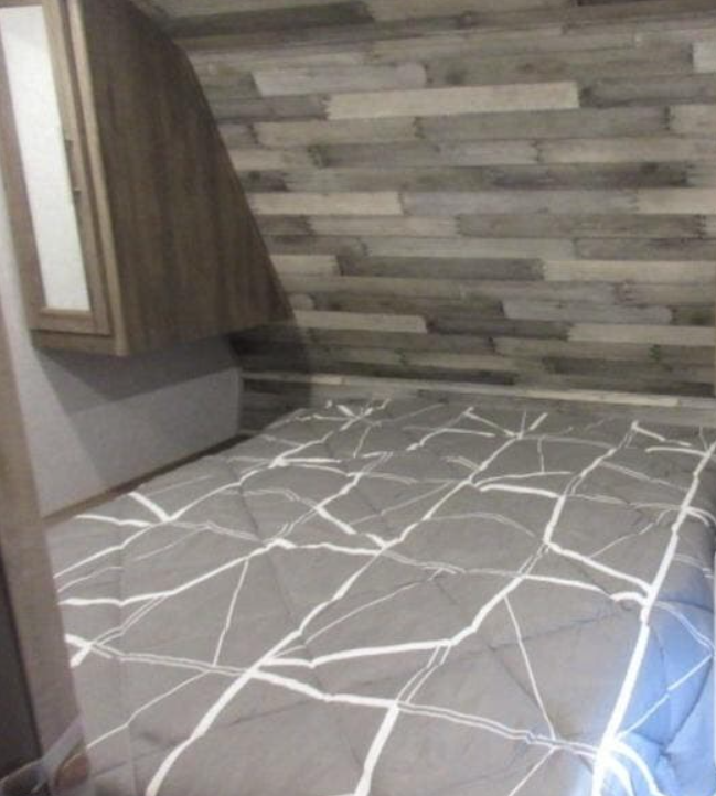 RV rental bedroom featuring a comfy grey bed with geometric pattern, wood accent wall, and storage cabinet.. Sportsmen Sportsmen SE 2020