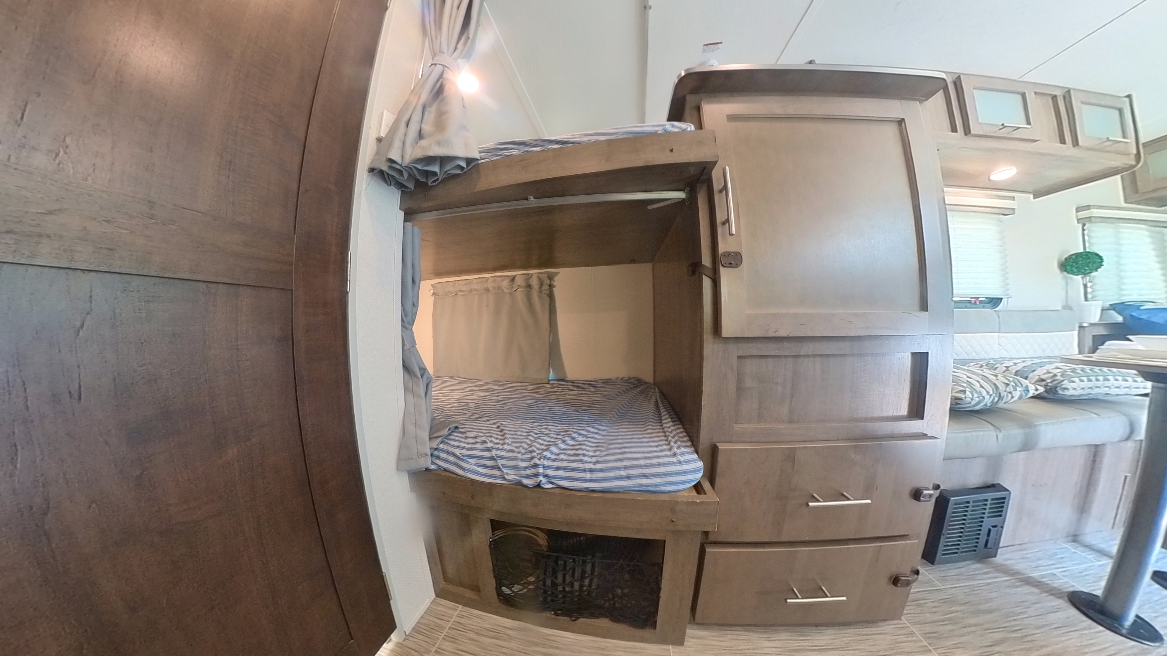 Inside an RV rental: two bunk beds with privacy curtains, ample storage, and a partial view of the dinette.. Forest River Other 2019