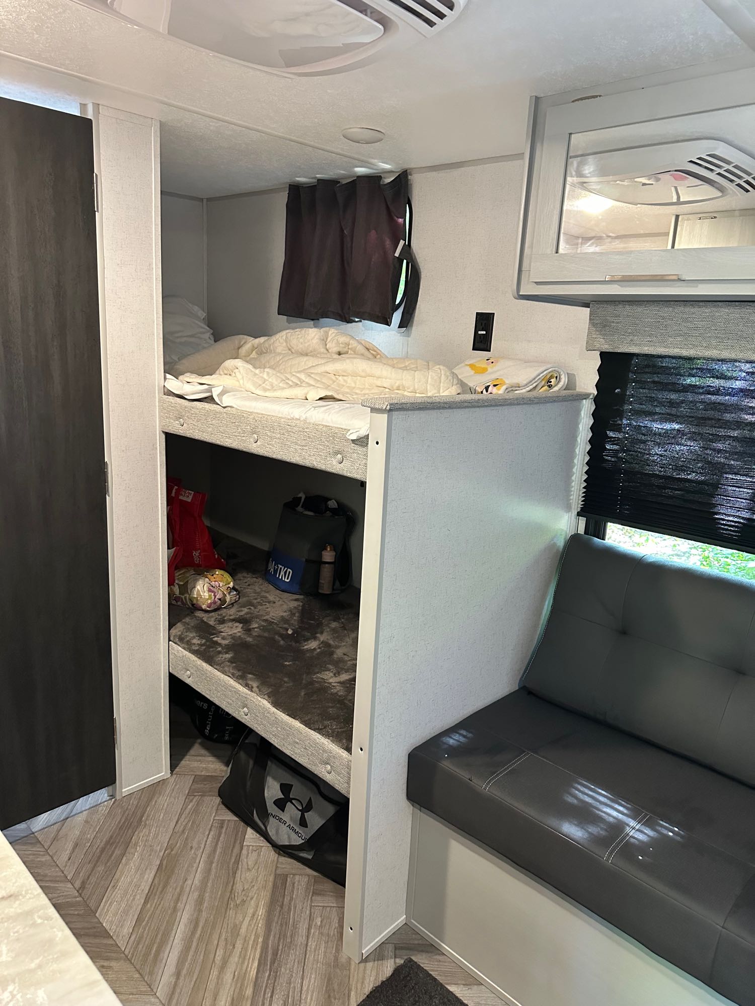 RV rental interior with bunk beds, sofa, & window showing outdoor view. Great for family camping.. Forest River Wildwood FSX 2023