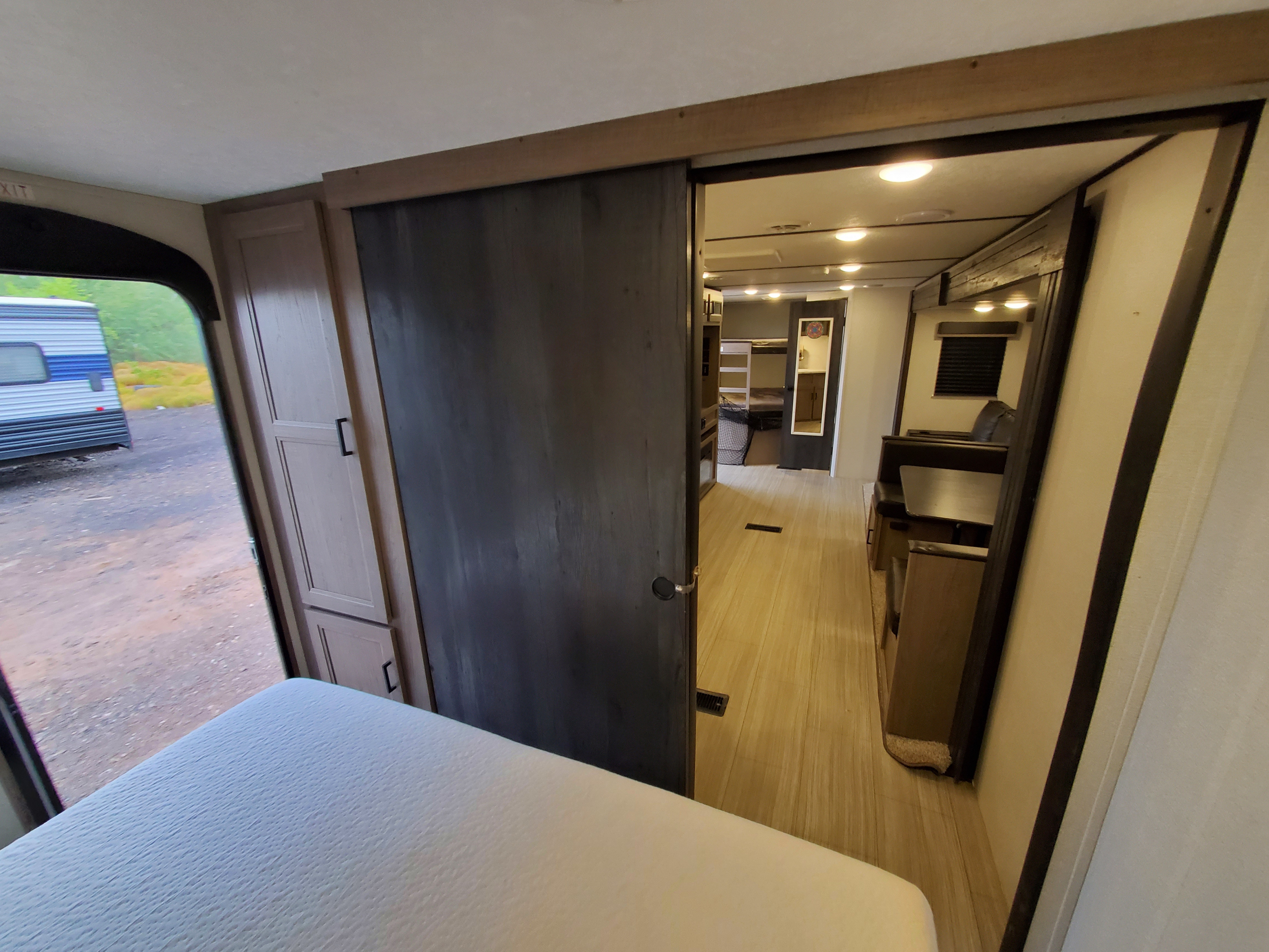 RV rental interior: View from the bedroom past a sliding door into the living space, revealing a dinette and bunks.. Keystone Hideout 2021