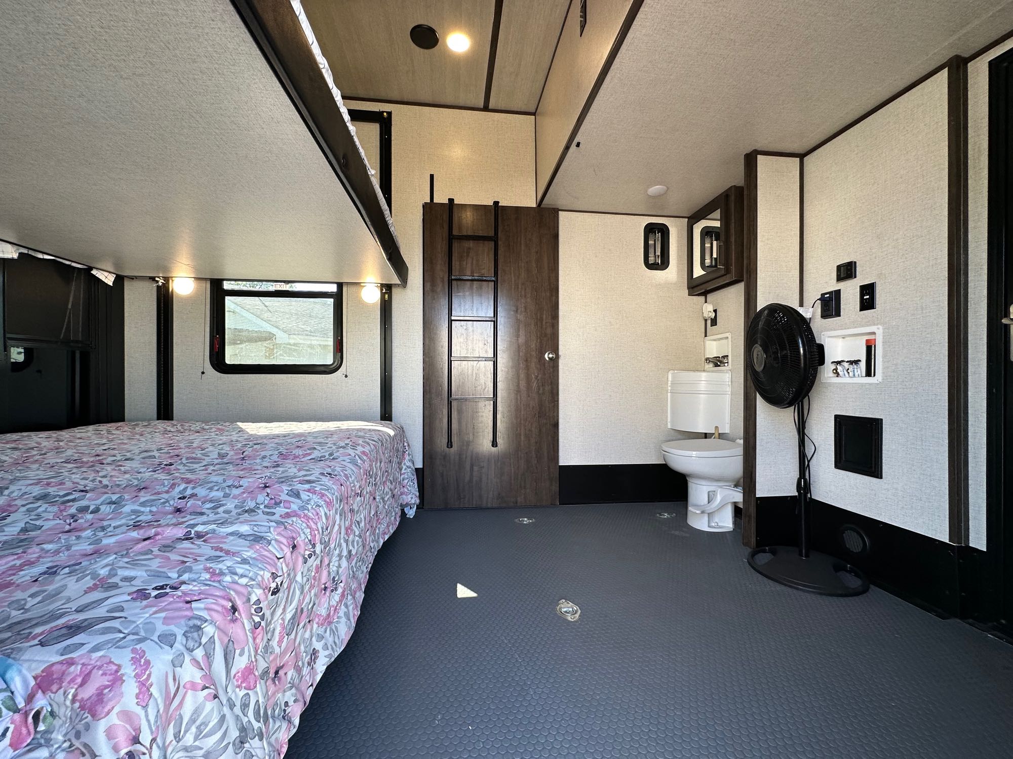 Inside an RV rental: a cozy bedroom with floral bedding, a compact bathroom with toilet, and durable utility floor. Ready for adventure!. Dutchmen Voltage Triton 4172 2022