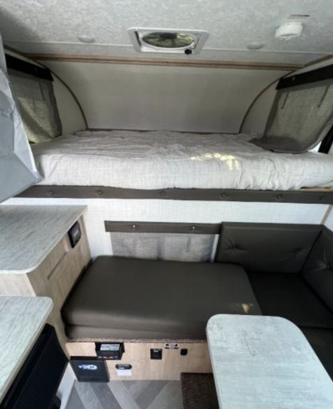Spacious RV rental interior featuring a cozy bed above a versatile dinette area, perfect for your next camping adventure.. Palomino Backpack Edition 2023