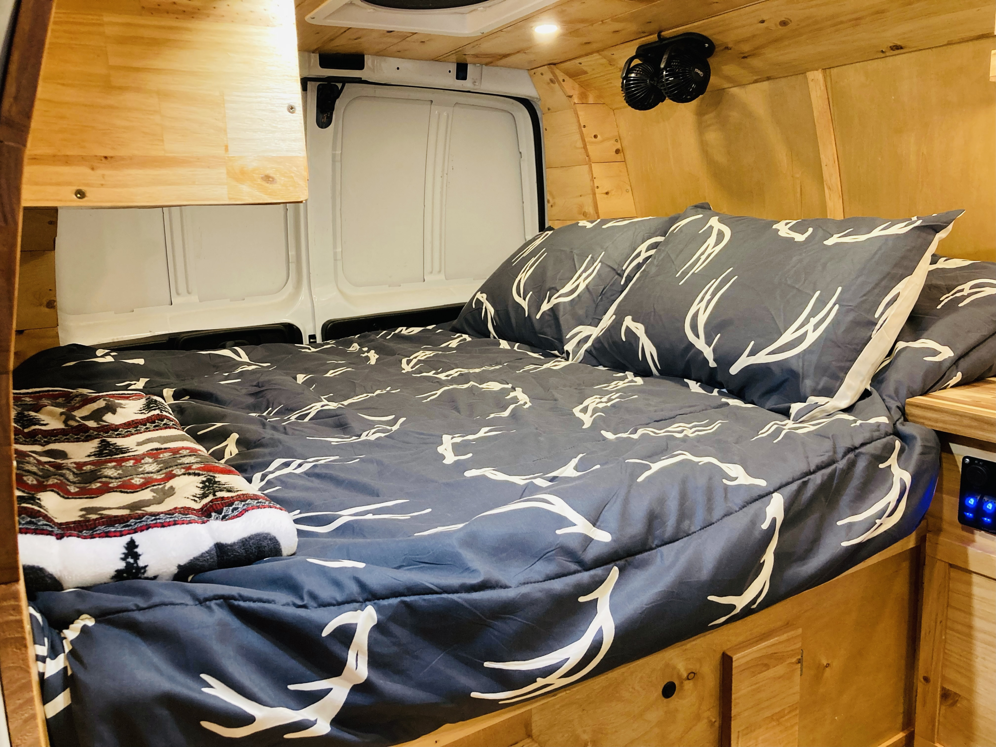 Sleep comfortably in this cozy **RV rental** van. Features antler print bedding, wooden paneling, and personal fans.. Gmc Savanna 2013