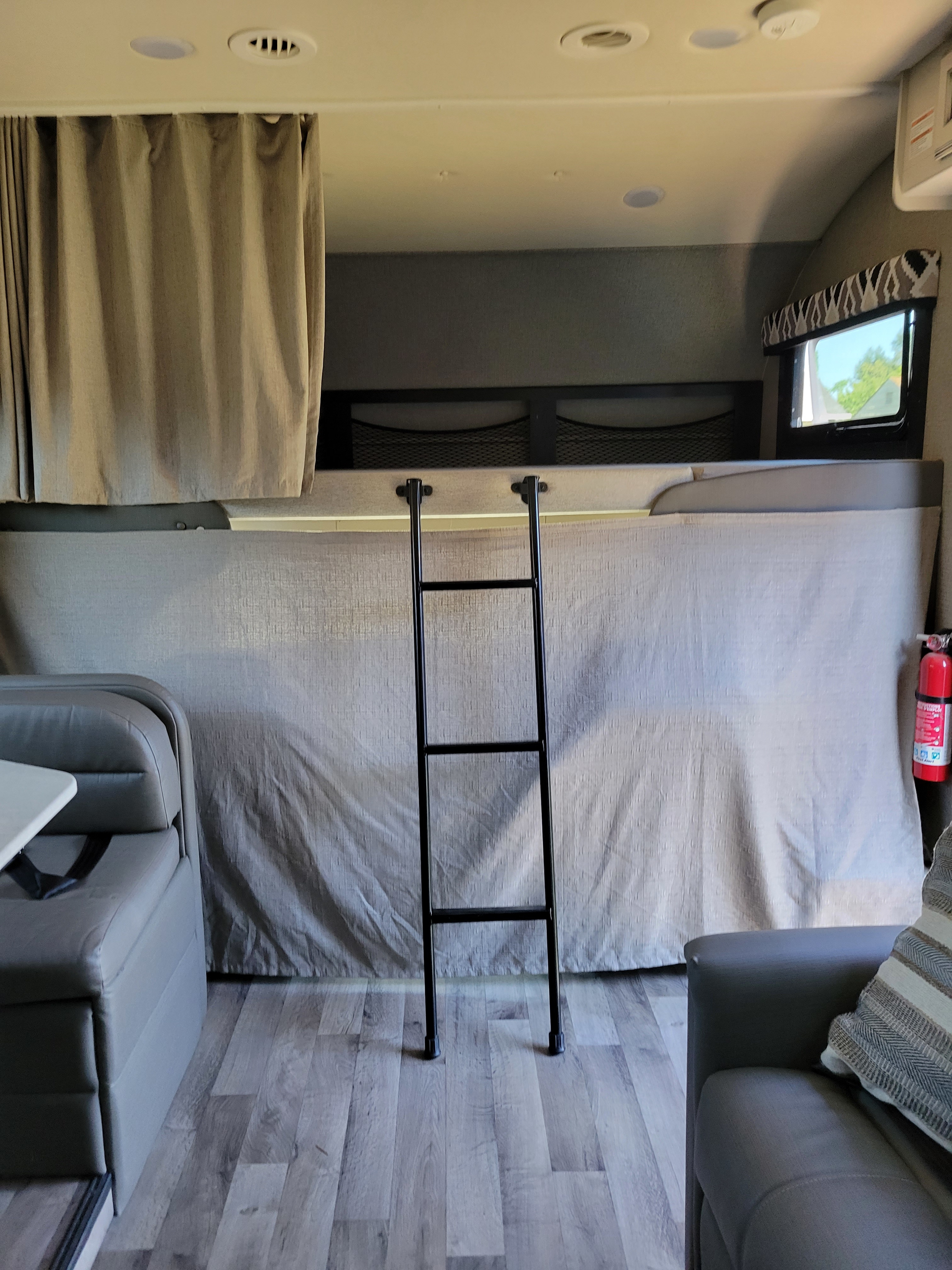 RV rental interior: view of a bunk bed with a ladder, featuring a dinette on the left and a sofa on the right.. Jayco Greyhawk 2020