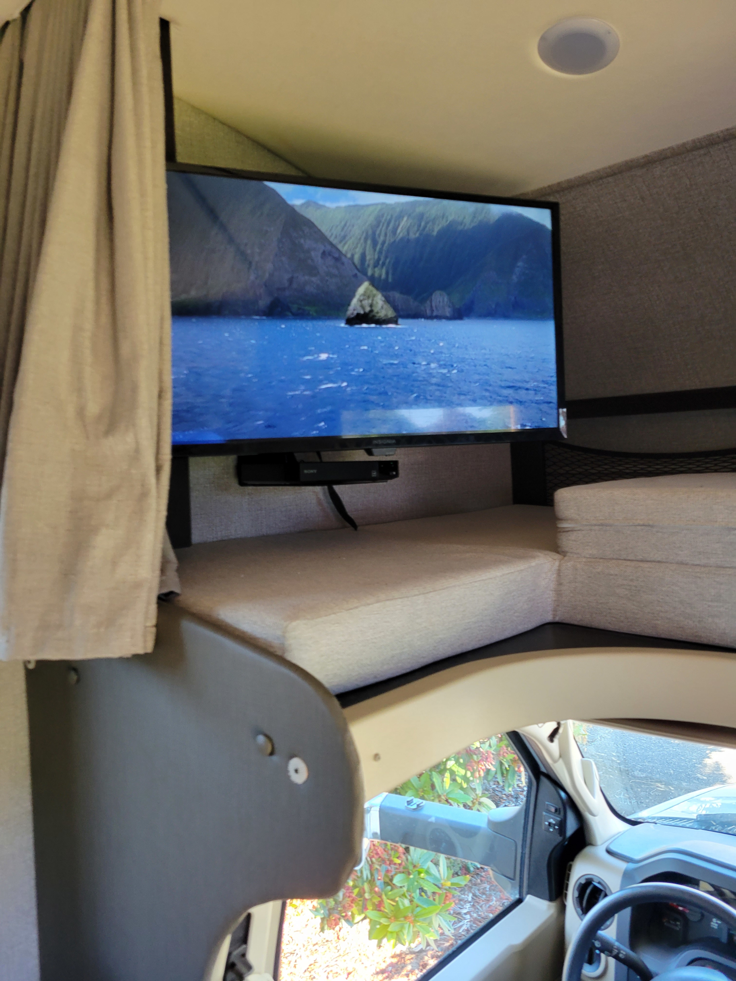 Inside an RV rental, the overhead bunk features a TV with a scenic view and a Sony player. Ideal for road trip entertainment.. Jayco Greyhawk 2020