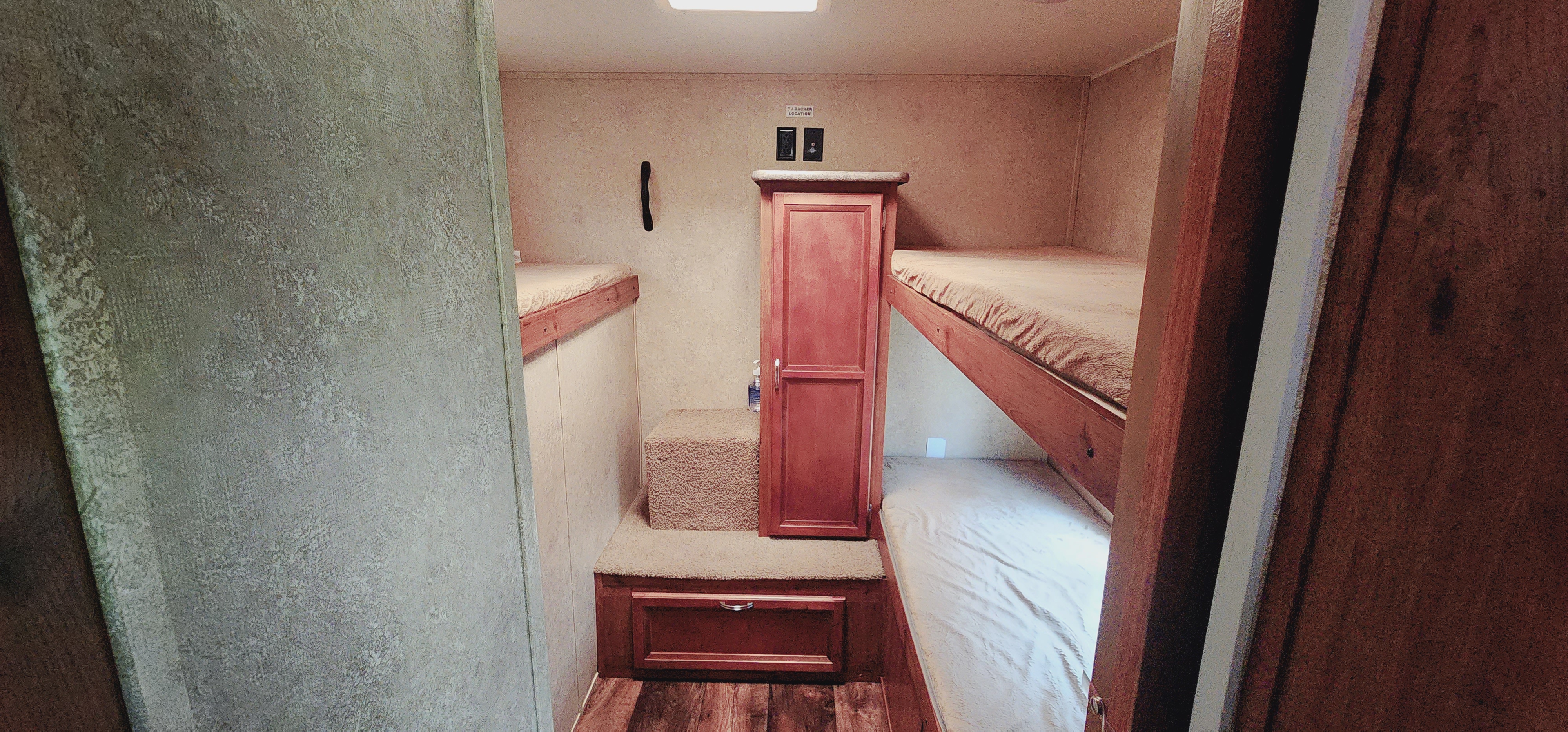 Cozy RV rental interior featuring a bunk bed setup with upper and lower berths, carpeted steps, and wood-look flooring.. Gulf Stream Ameri-Lite 2017