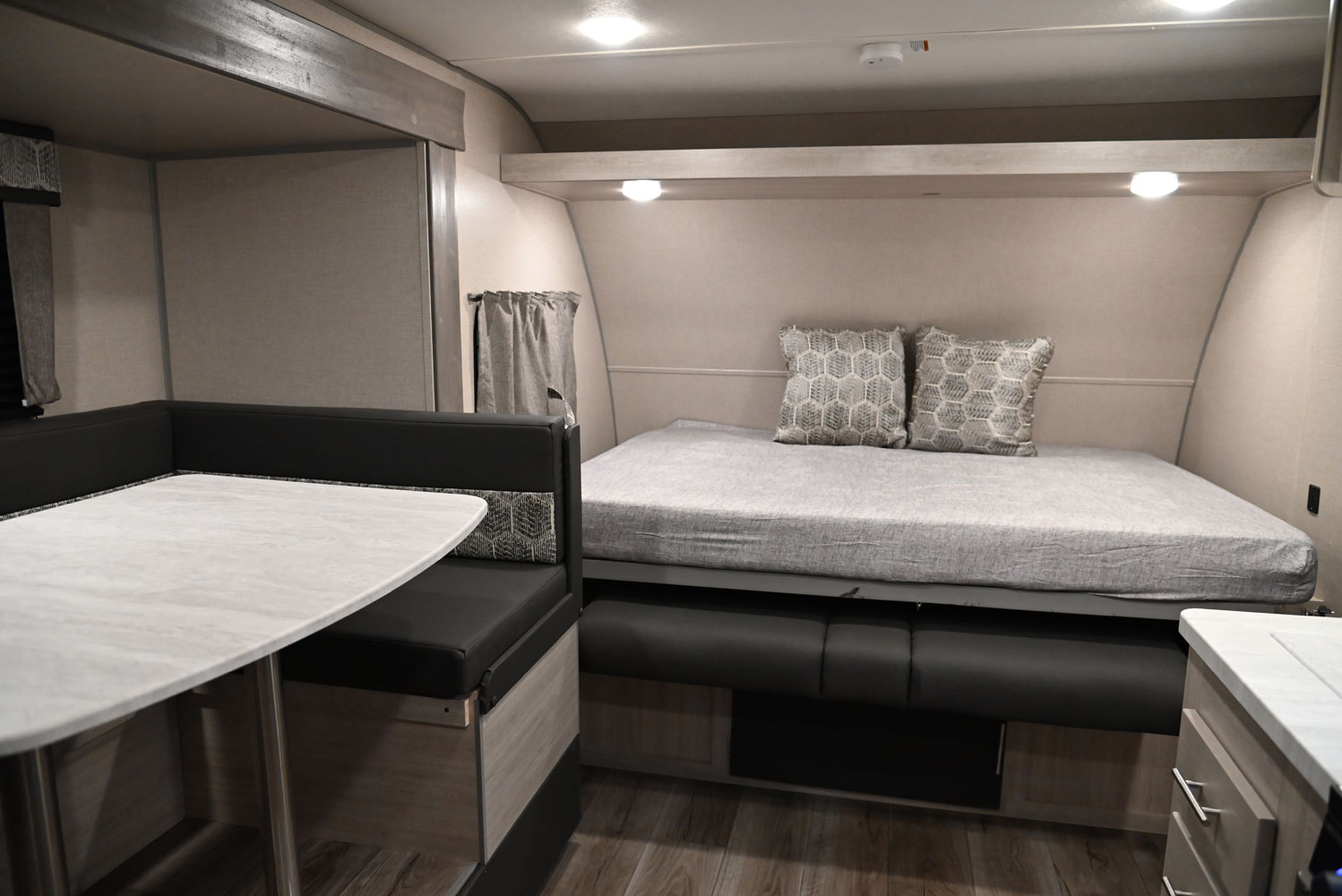 Cozy RV rental interior featuring a dinette with black bench seating and a comfortable bed with two decorative pillows.. Coachmen Catalina Summit 184BHS 2022