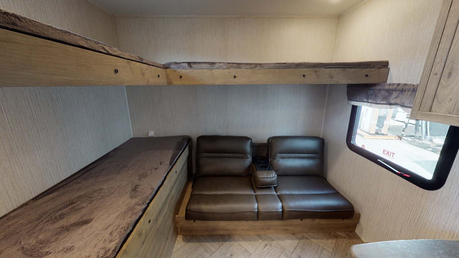 RV rental interior featuring a bunk bed over a lower sleeping area and a sofa with cupholders next to a window.. Forest River Palomino Puma 2023