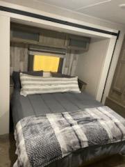 Cozy RV rental bedroom with a grey bed, striped pillows & plaid blanket. Ideal for comfortable travel adventures.. Forest River Puma 2021