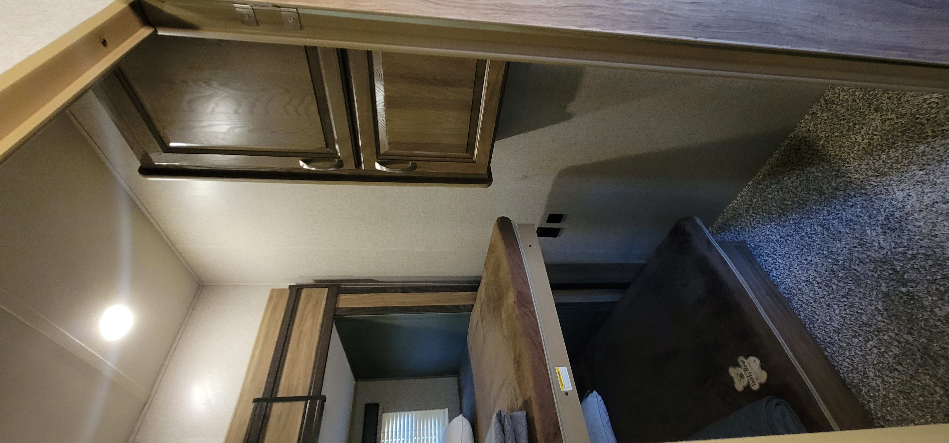 RV rental interior: Overhead wooden cabinets, a bunk bed area with stacked mattresses, and a carpeted floor with a pet bed are visible.. Atlas Atlas Fifth Wheel 2019