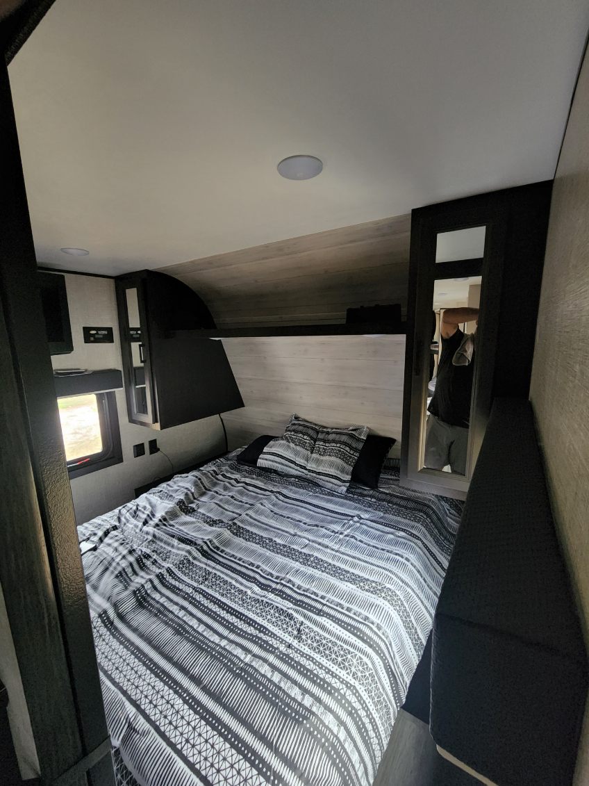 An RV rental bedroom with black and white patterned bedding. It features a window, built-in storage, and an upper bunk.. Jayco Jay Flight SLX 2022