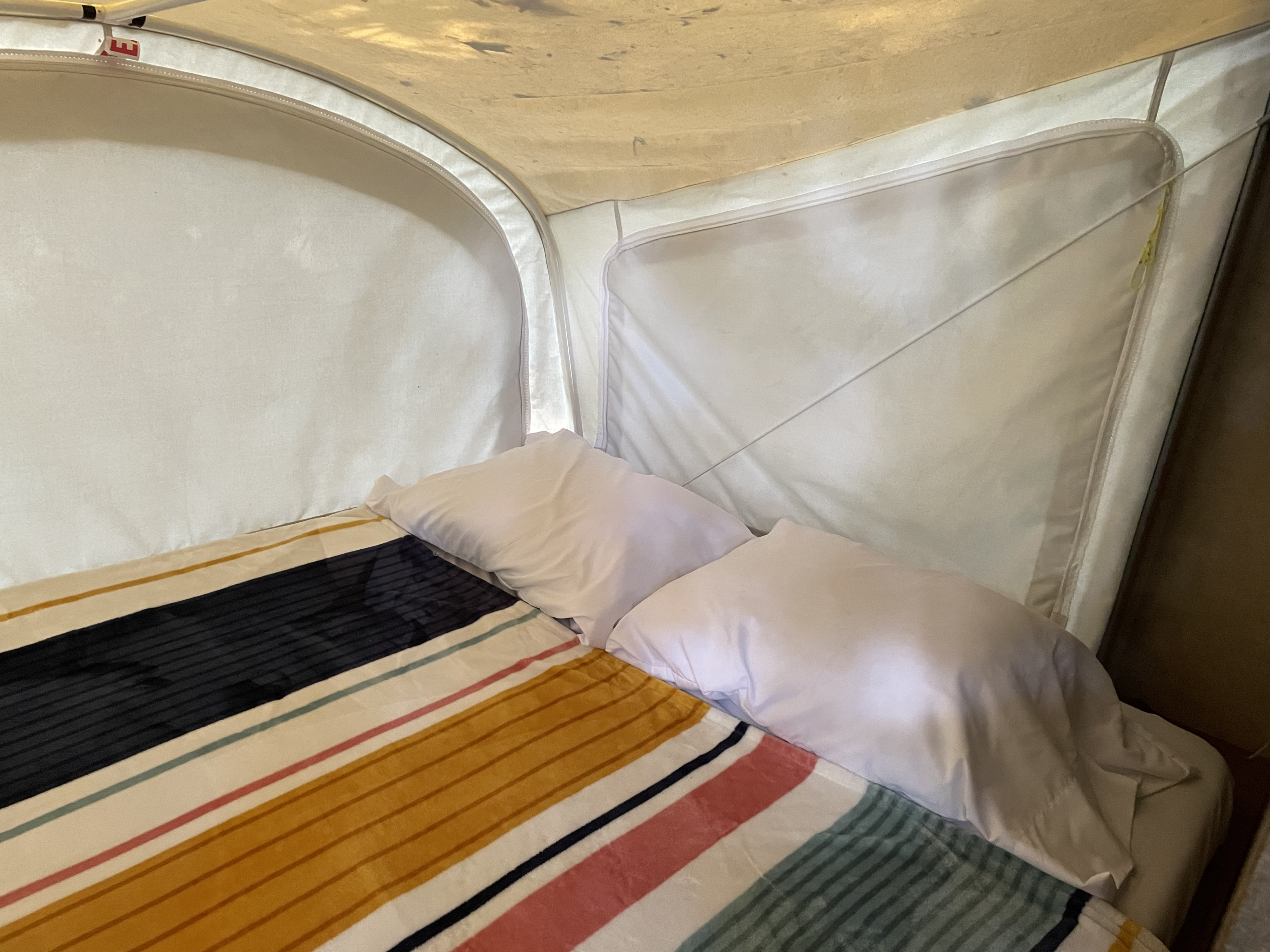 A cozy RV rental interior: bed with white pillows and a vibrant striped blanket, perfect for your next camper trip.. Starcraft Launch 2016
