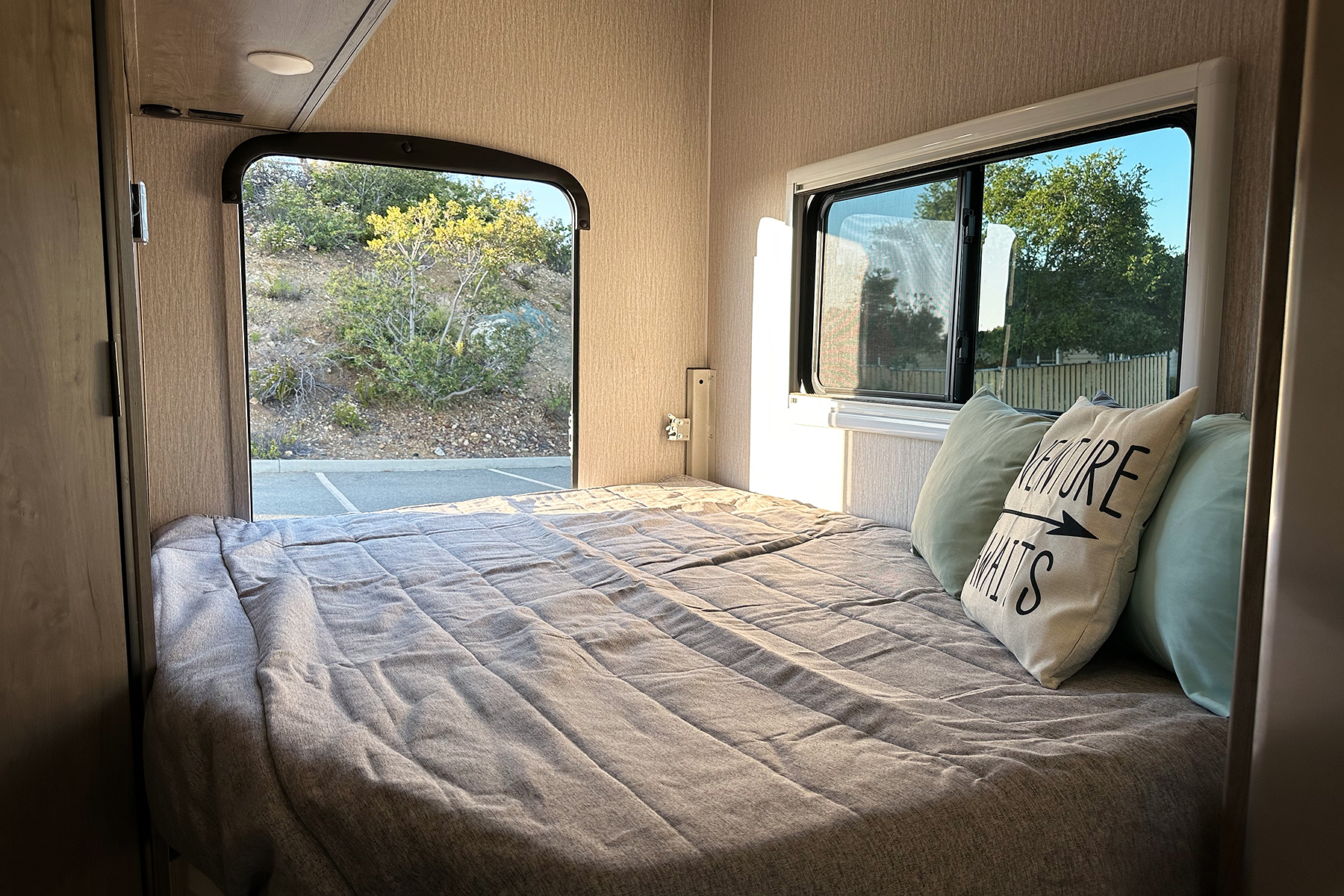 Comfortable RV rental bedroom interior, featuring a cozy bed with pillows, and bright windows revealing scenic outdoor views.. Forest River Coachmen Cross Trail XL 2022