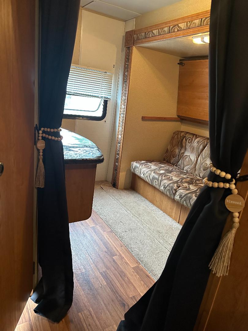 Explore this cozy RV rental interior, featuring a compact living space with window, seating, and decor.. Forest River Wildwood 2010